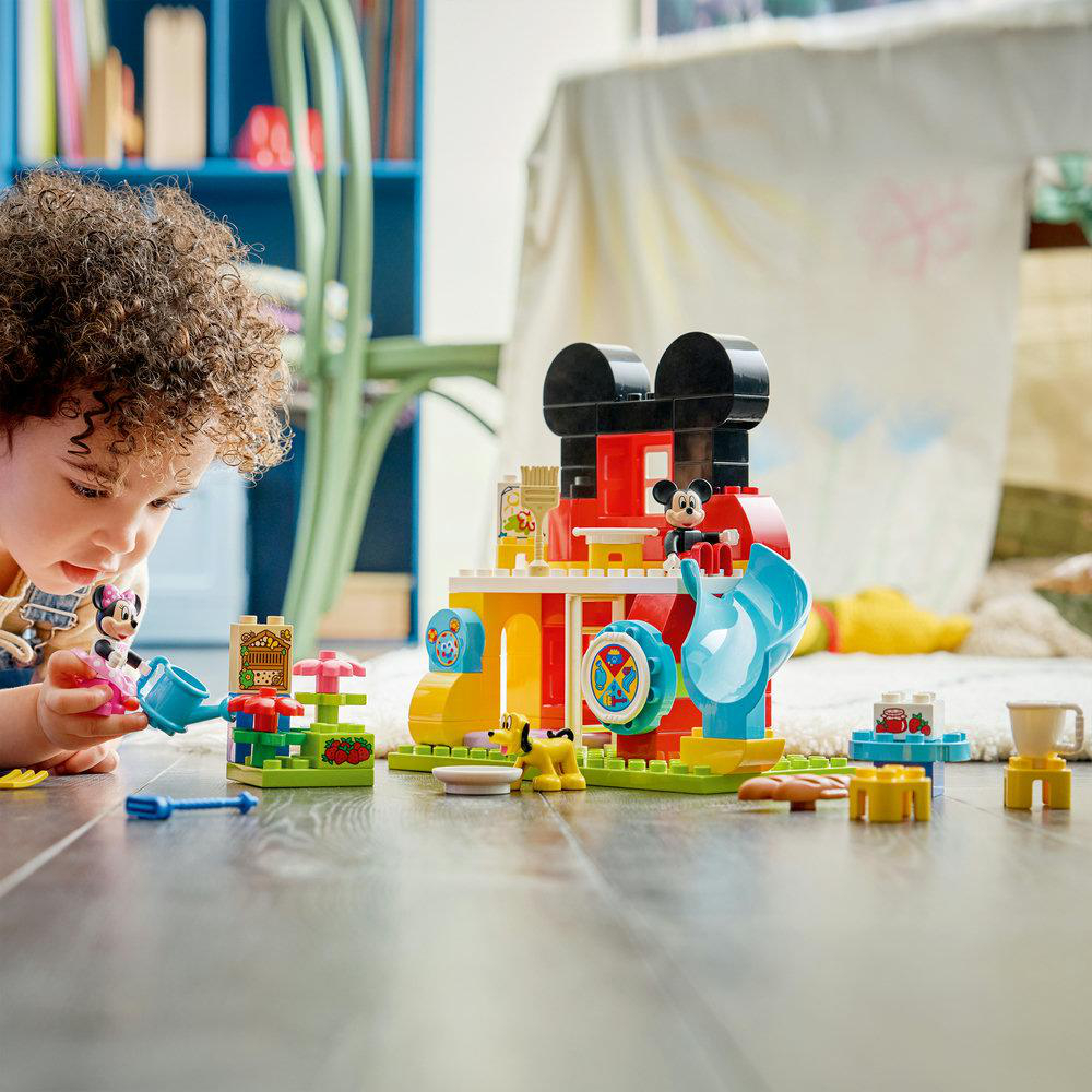 Ein Kind spielt mit Mickey Maus Lego Duplo. Bausteine und Figuren auf dem Boden.