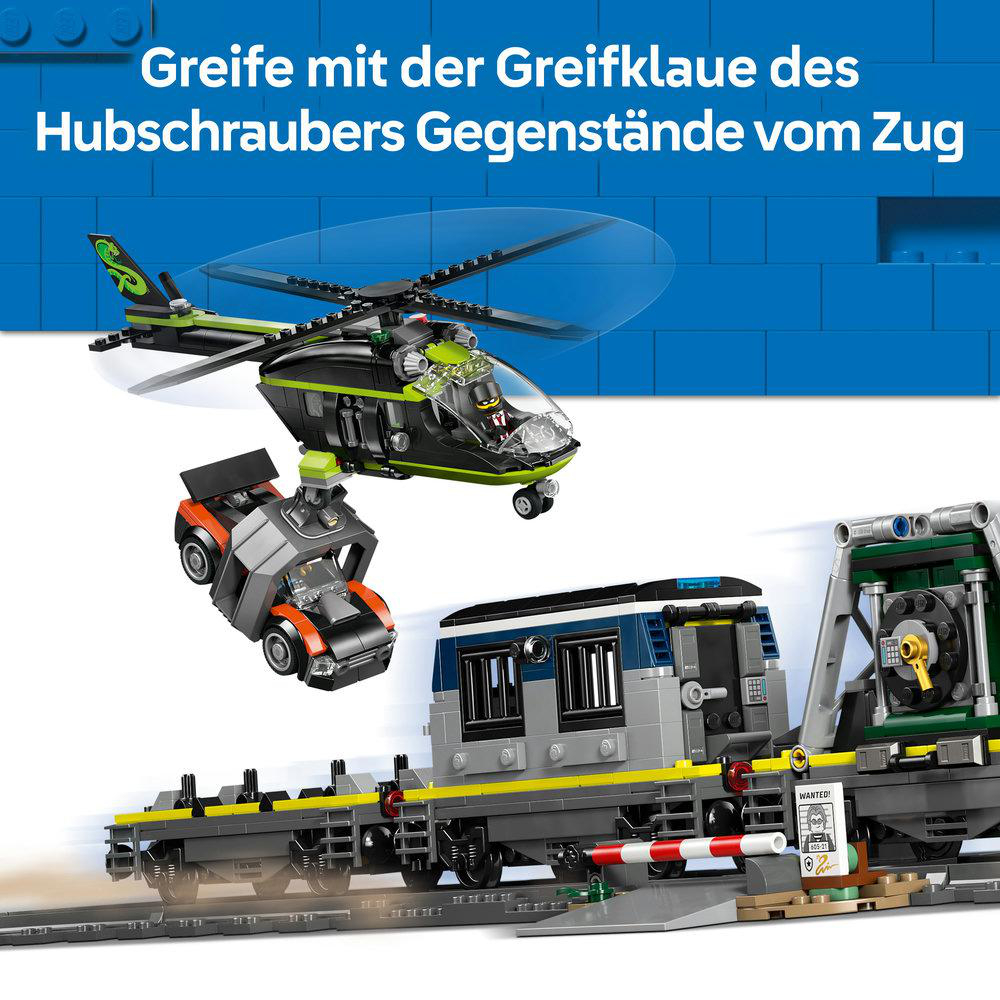Ein Hubschrauber mit Greifklaue hebt ein orange-graues Fahrzeug über einem Zug.