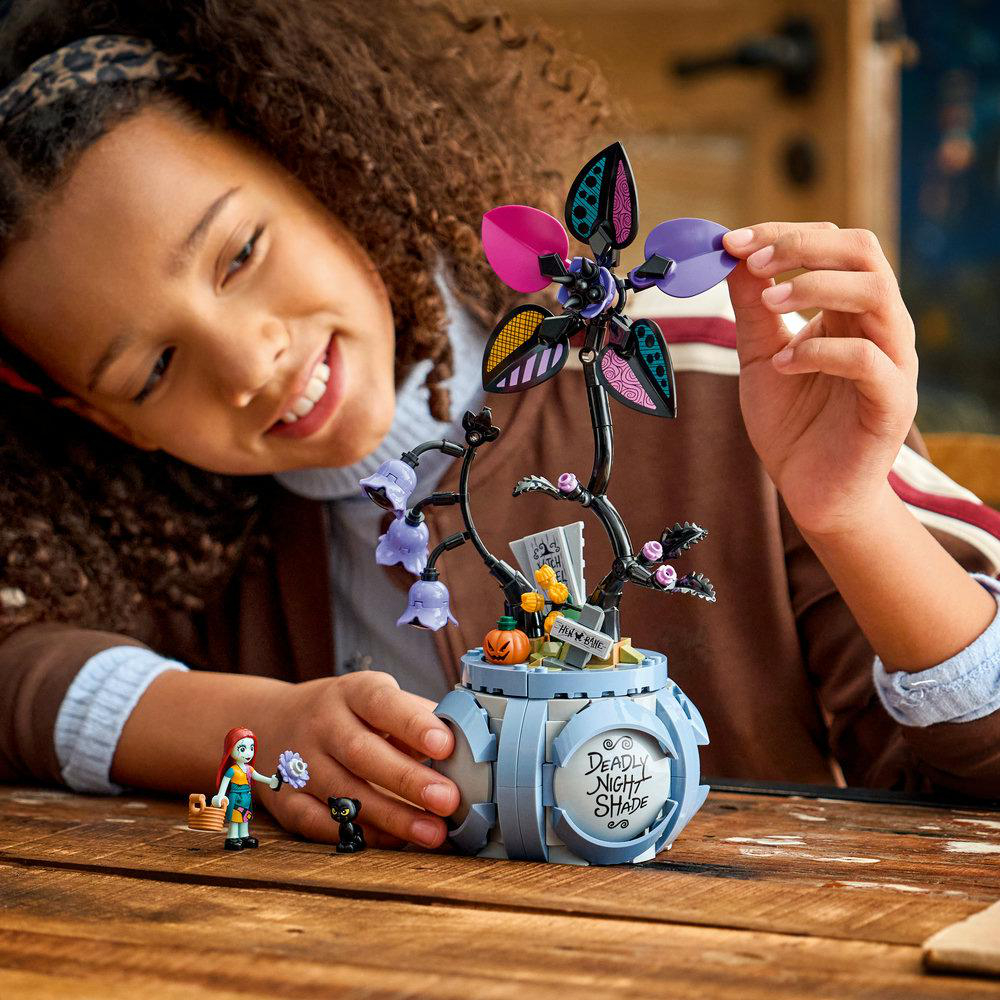 Ein Mädchen baut ein LEGO-Set mit einer Blume, einem Kürbis und Figuren.