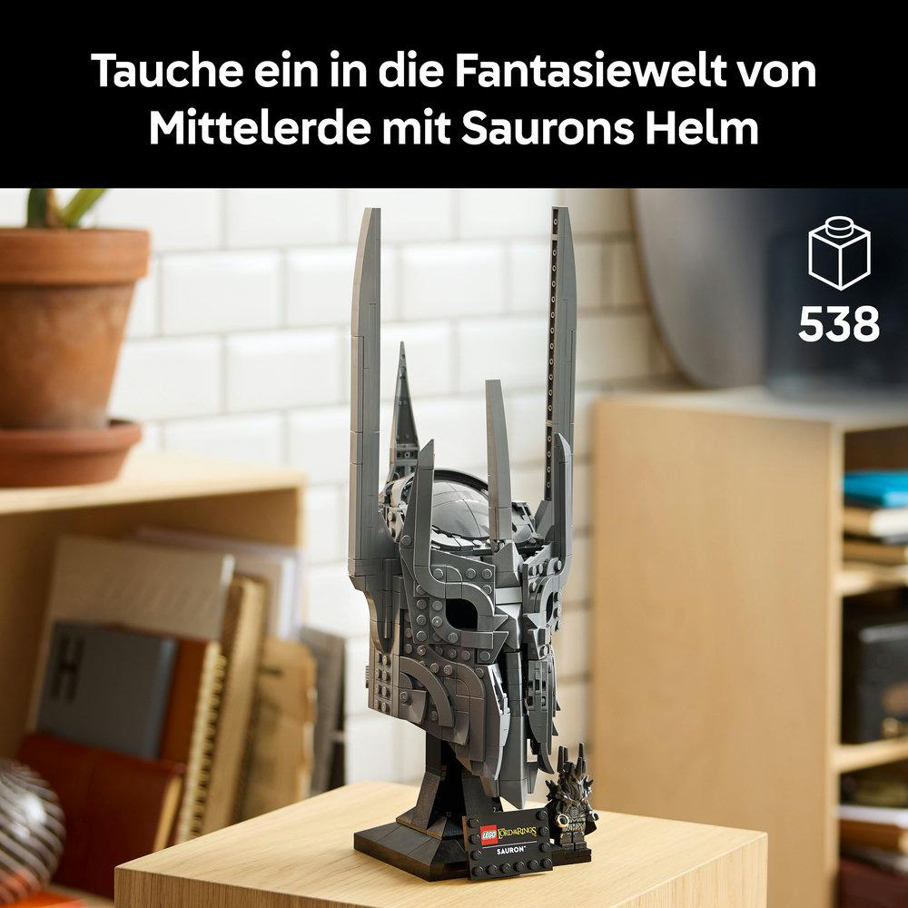 Grauer Lego Sauron Helm mit kleinem Minifiguren-Krieger und Pflanze im Hintergrund.