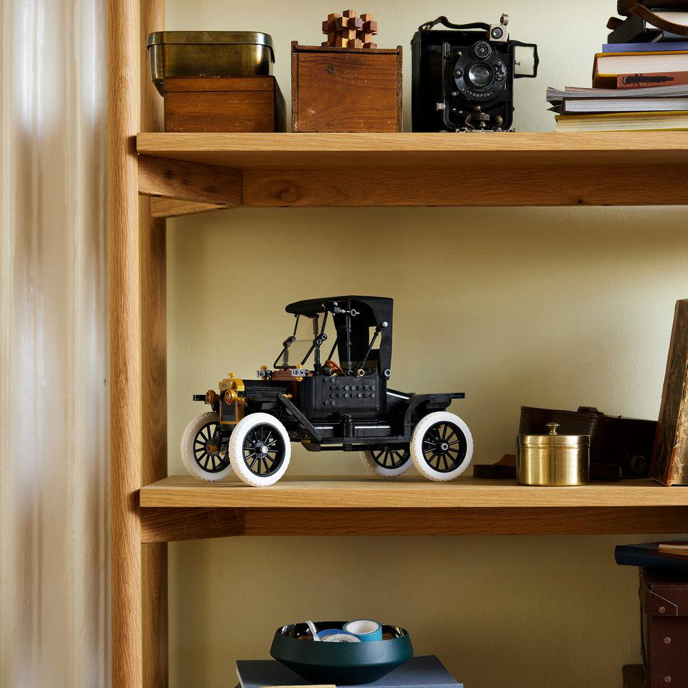 Ein schwarzes Oldtimer-Modellauto steht auf einem Regal neben Vintage-Objekten.
