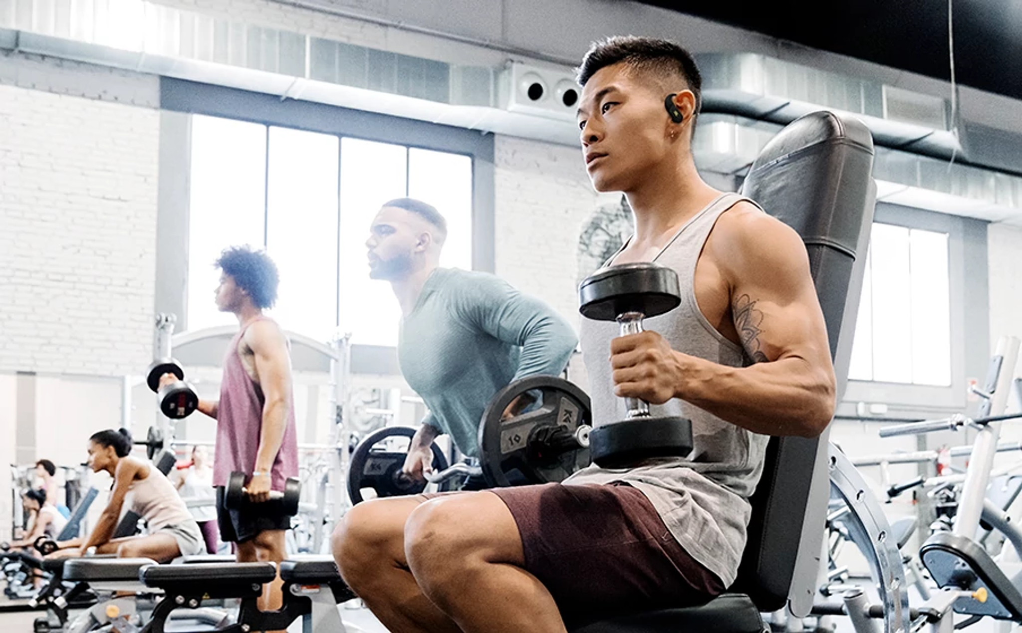 Männer trainieren mit Hanteln in einem Fitnessstudio.