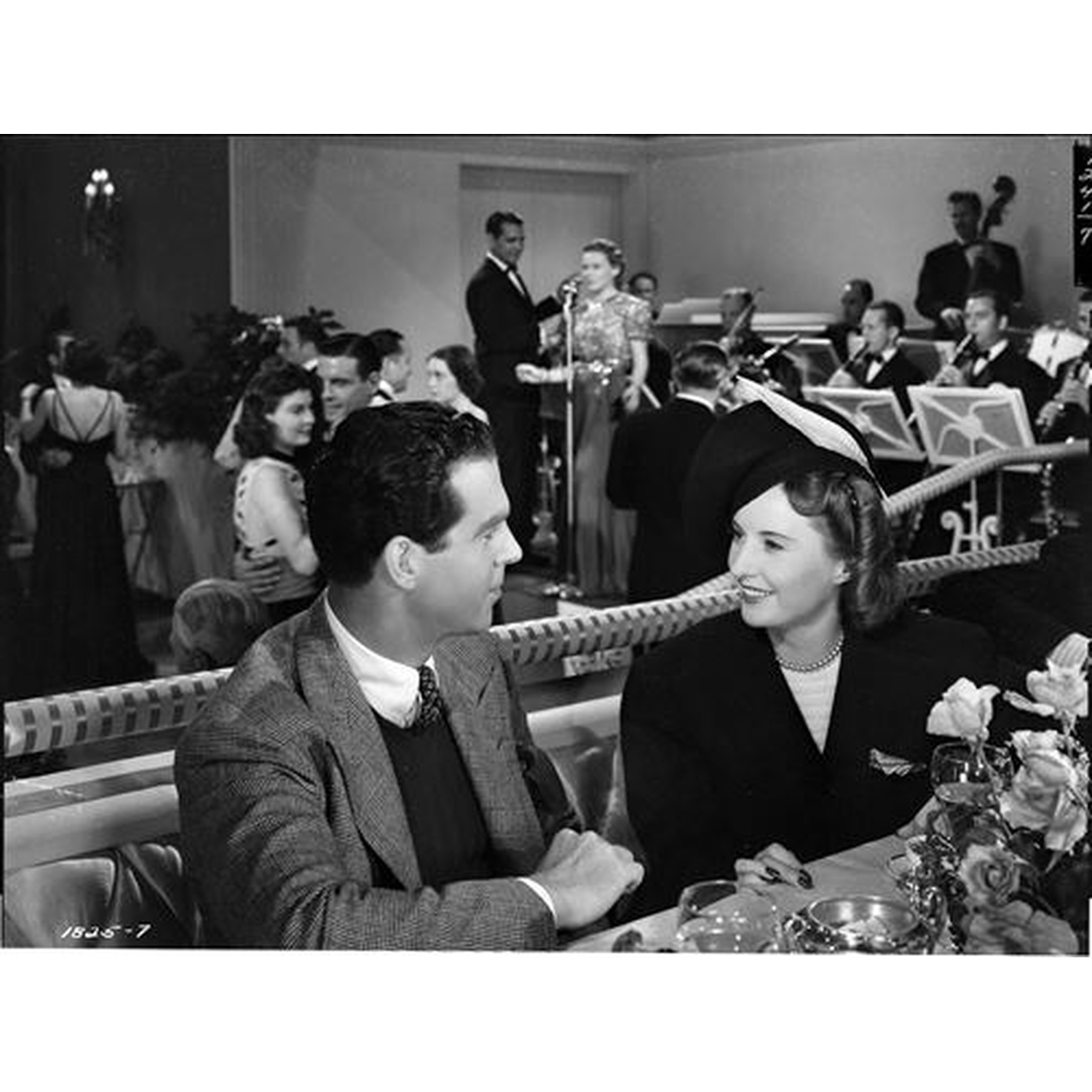 Un couple assis à une table pendant qu'un groupe joue en arrière-plan.