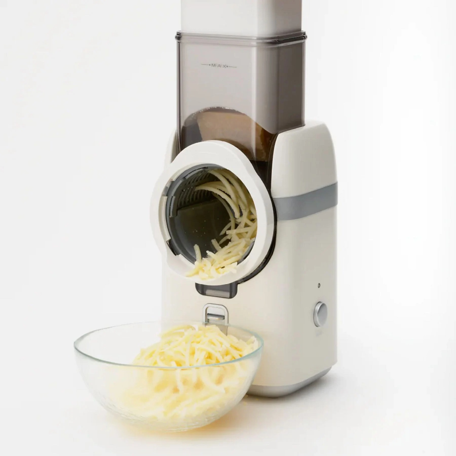 An electric cheese grater with cheese in a glass bowl.