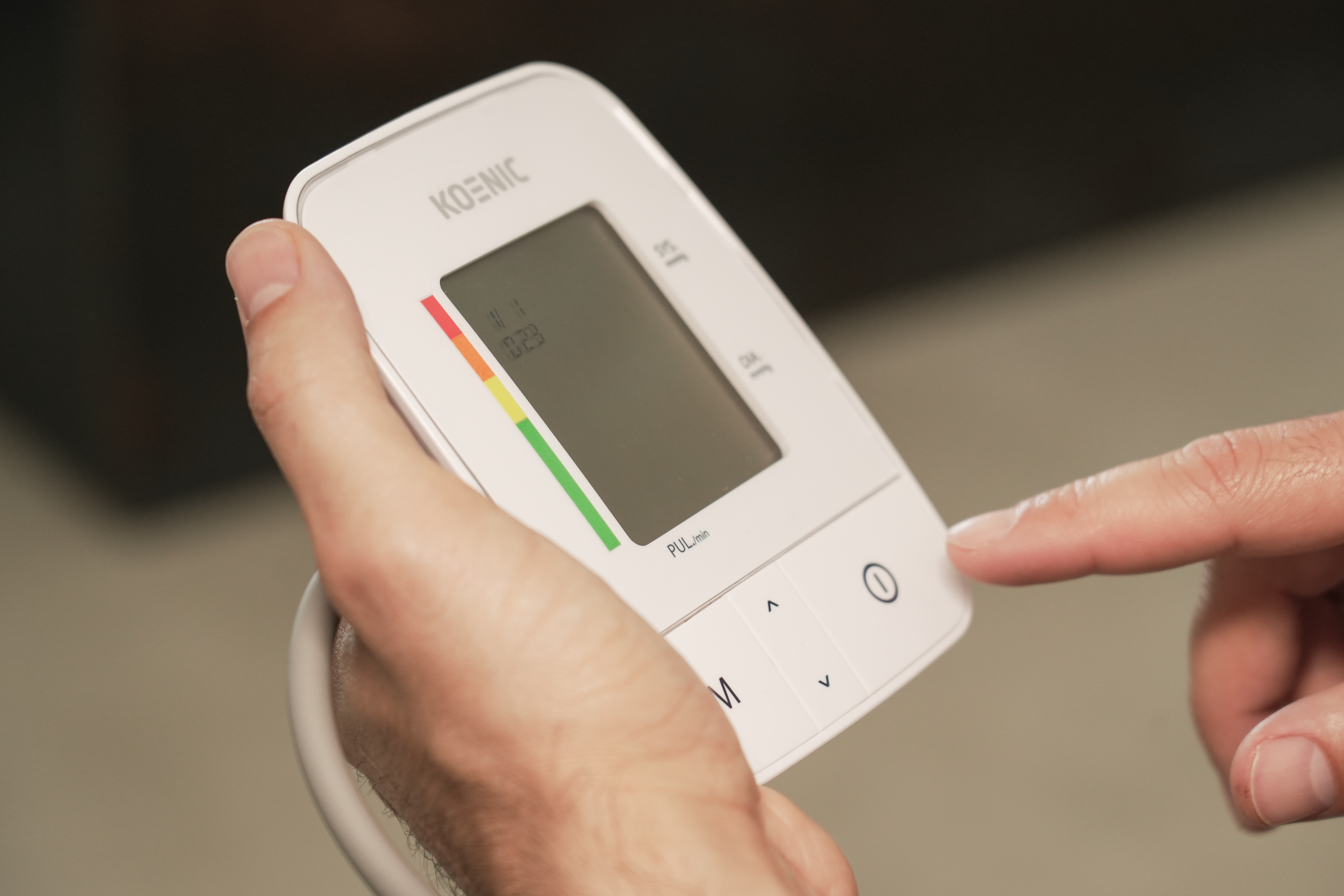 Palec naciska na biały ciśnieniomierz z wyświetlaczem.