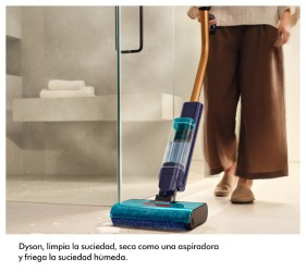 Una persona limpia un suelo de baño con una aspiradora Dyson.