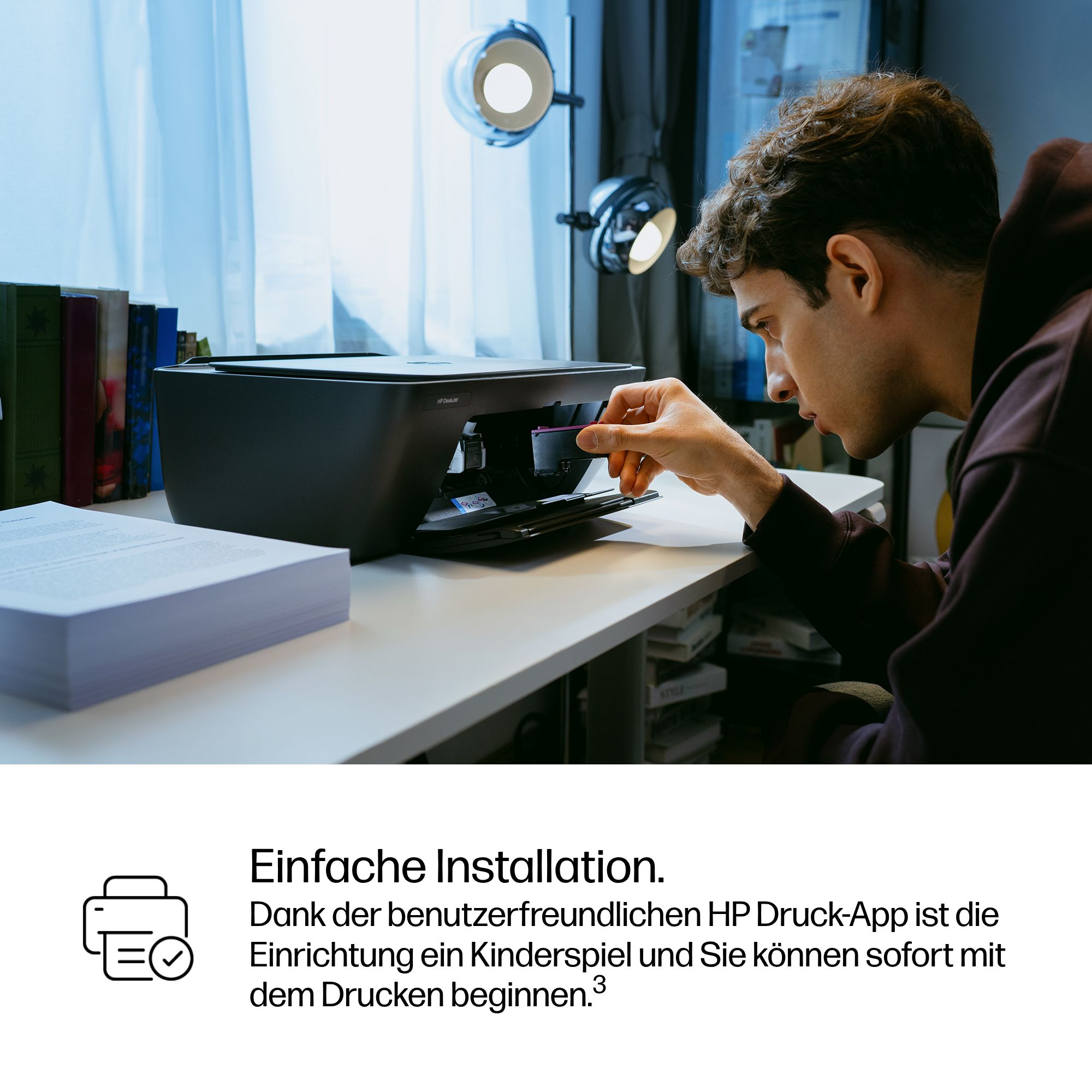 Mann setzt Tintenpatrone in HP Drucker ein, Stapel Papier liegt daneben.