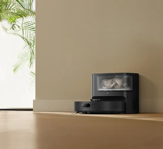 Czarny robot sprzątający obok stacji ładującej wypełnionej kurzem.