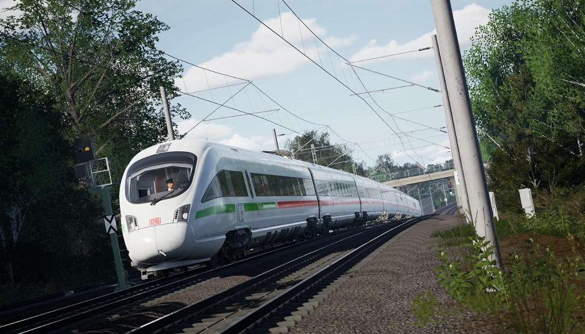 Ein weißer ICE-Zug fährt auf Schienen durch eine grüne Landschaft unter Oberleitungen.