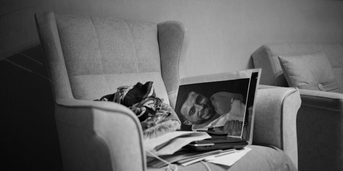 Ein Sessel mit Kleidung und einem Foto eines lächelnden Mannes.