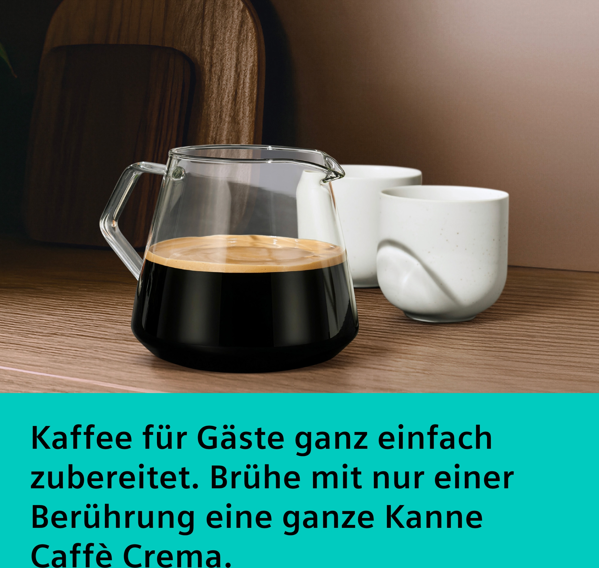 Glas Karaffe mit Kaffee und zwei weißen Tassen auf Holztisch.