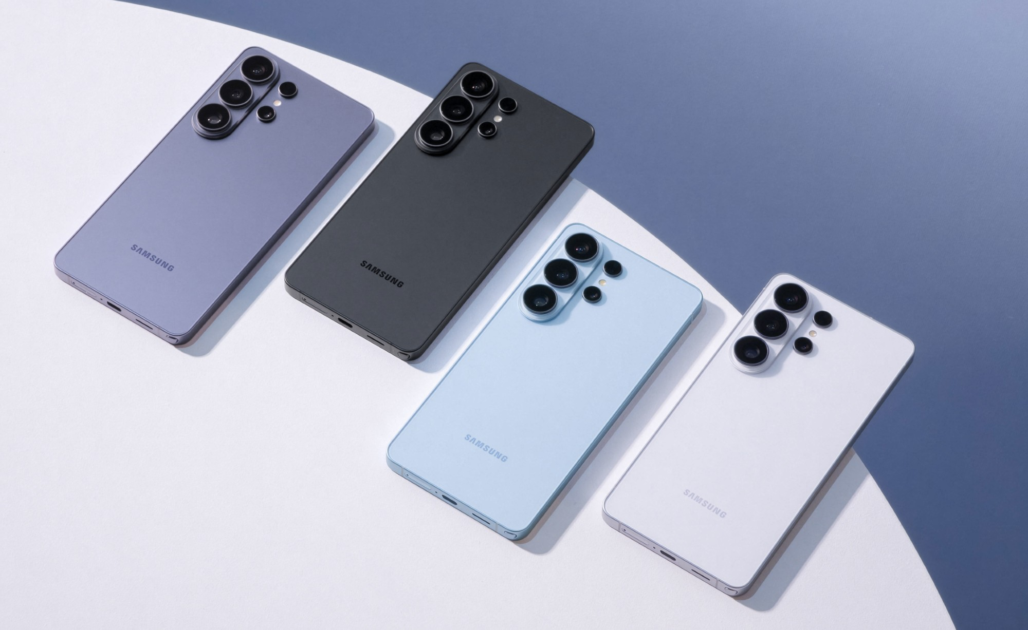 Cztery smartfony Samsung w kolorach fioletowym, czarnym, jasnoniebieskim i białym na białym tle.