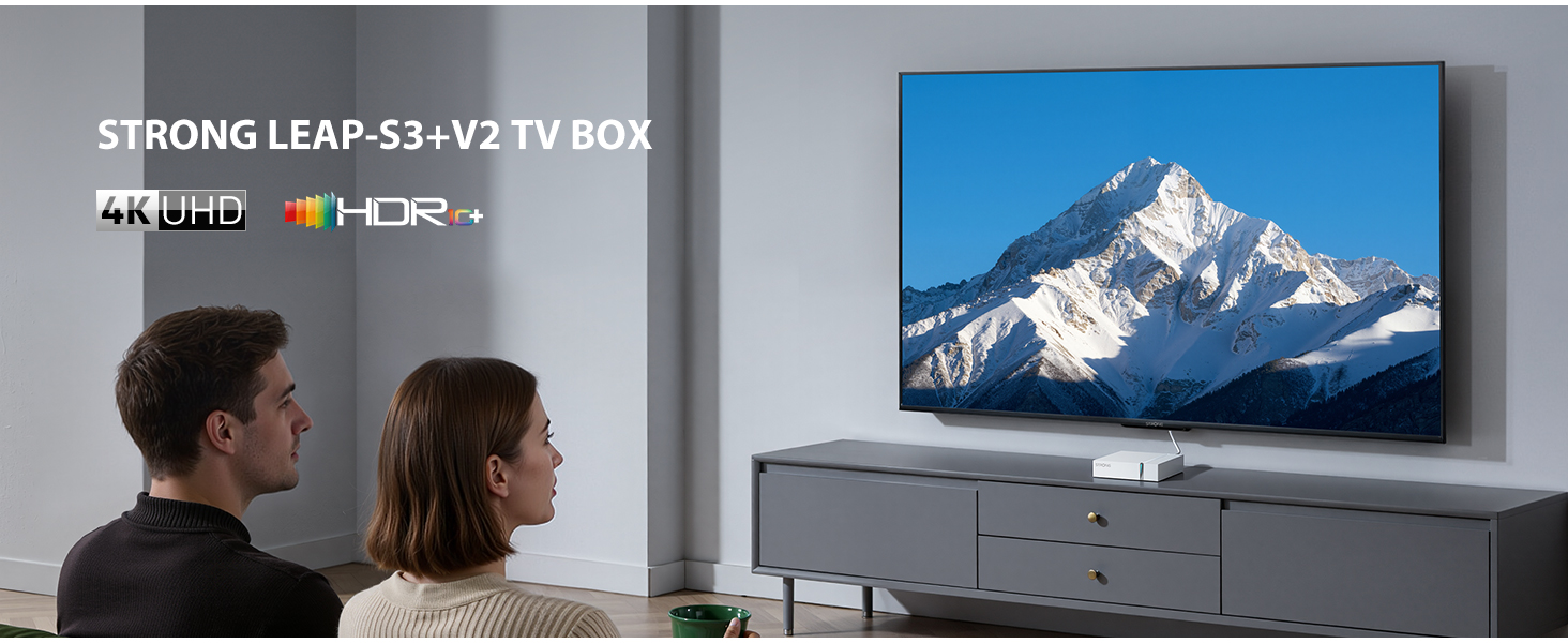 Una pareja mira un televisor con paisaje de montaña. STRONG LEAP-S3+V2 TV BOX.
