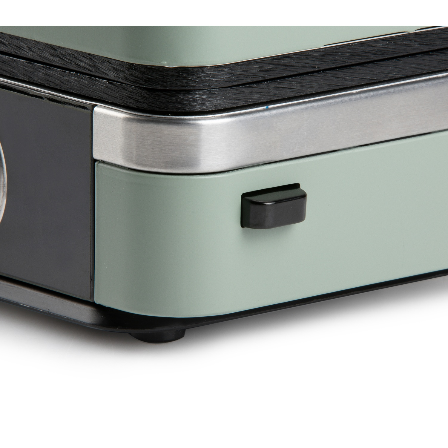 Close-up of a mint green appliance with black and silver accents and a black button.