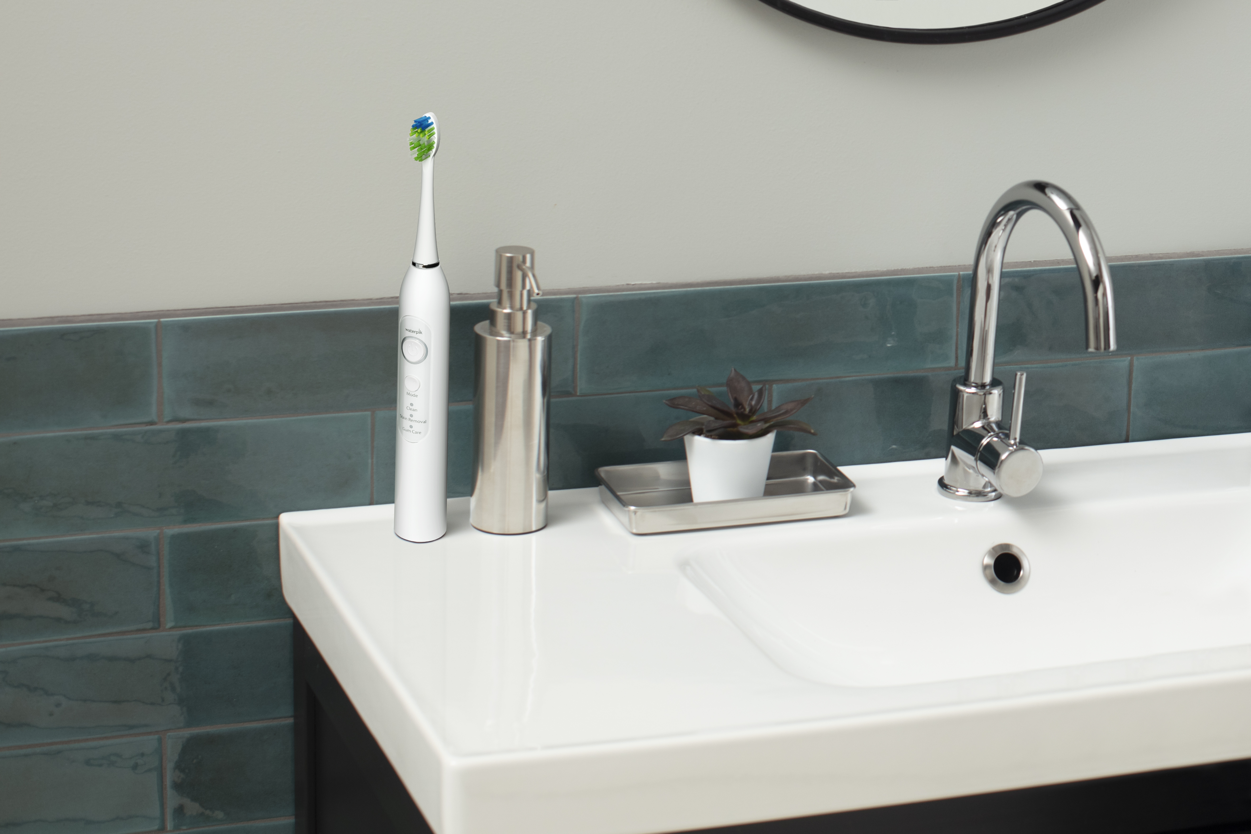 Biała szczoteczka elektryczna i dozownik mydła na umywalce.