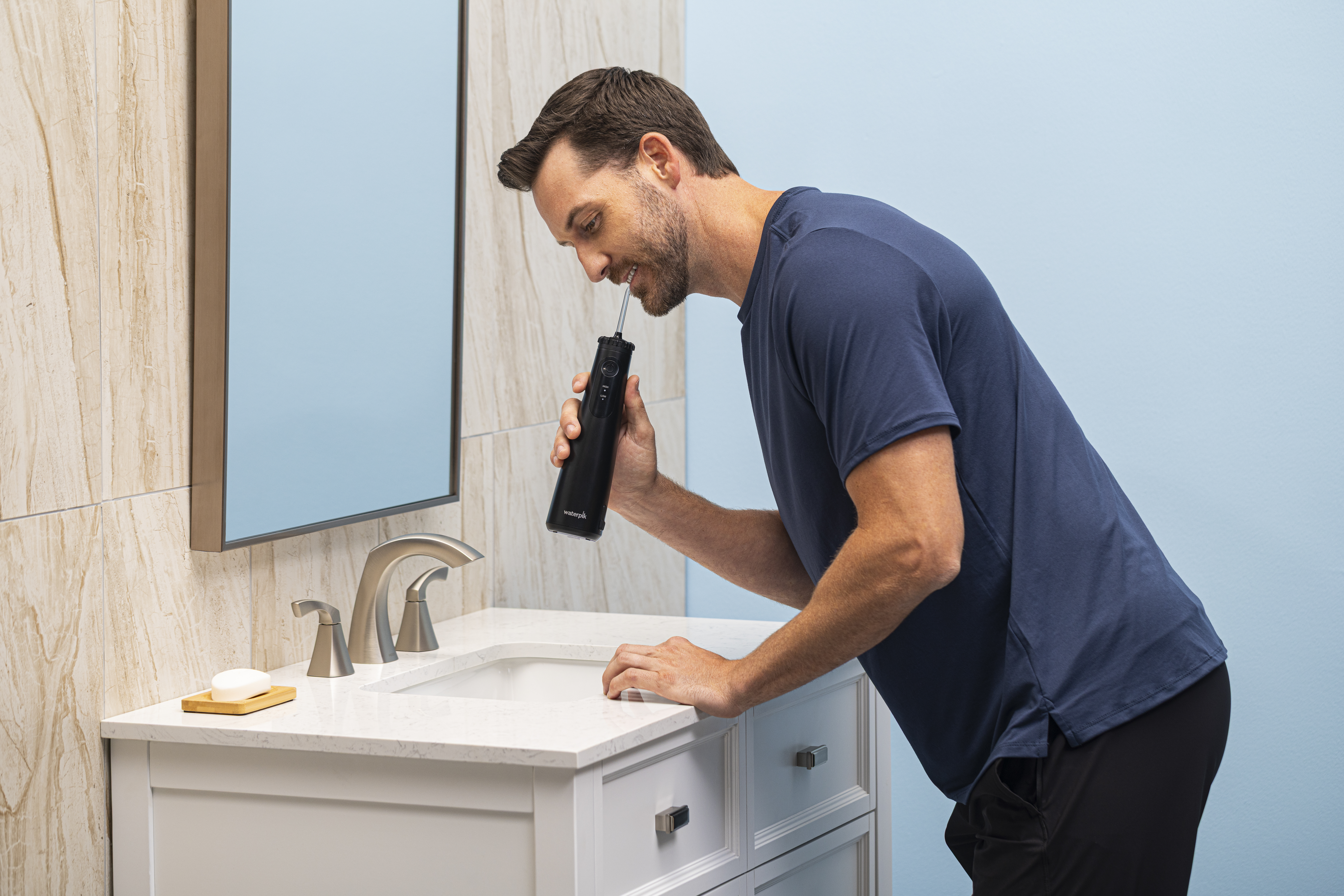 Mężczyzna używa czarnej irygatora w łazience.