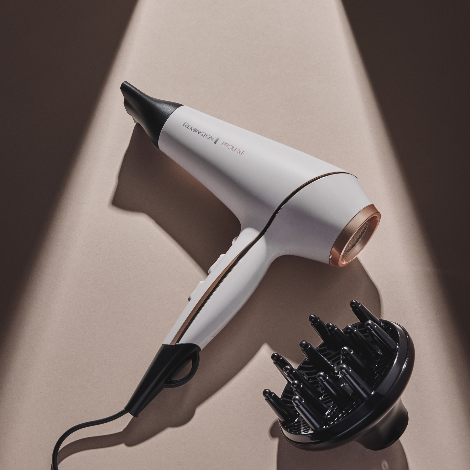 Un asciugacapelli Remington bianco con diffusore su sfondo beige.