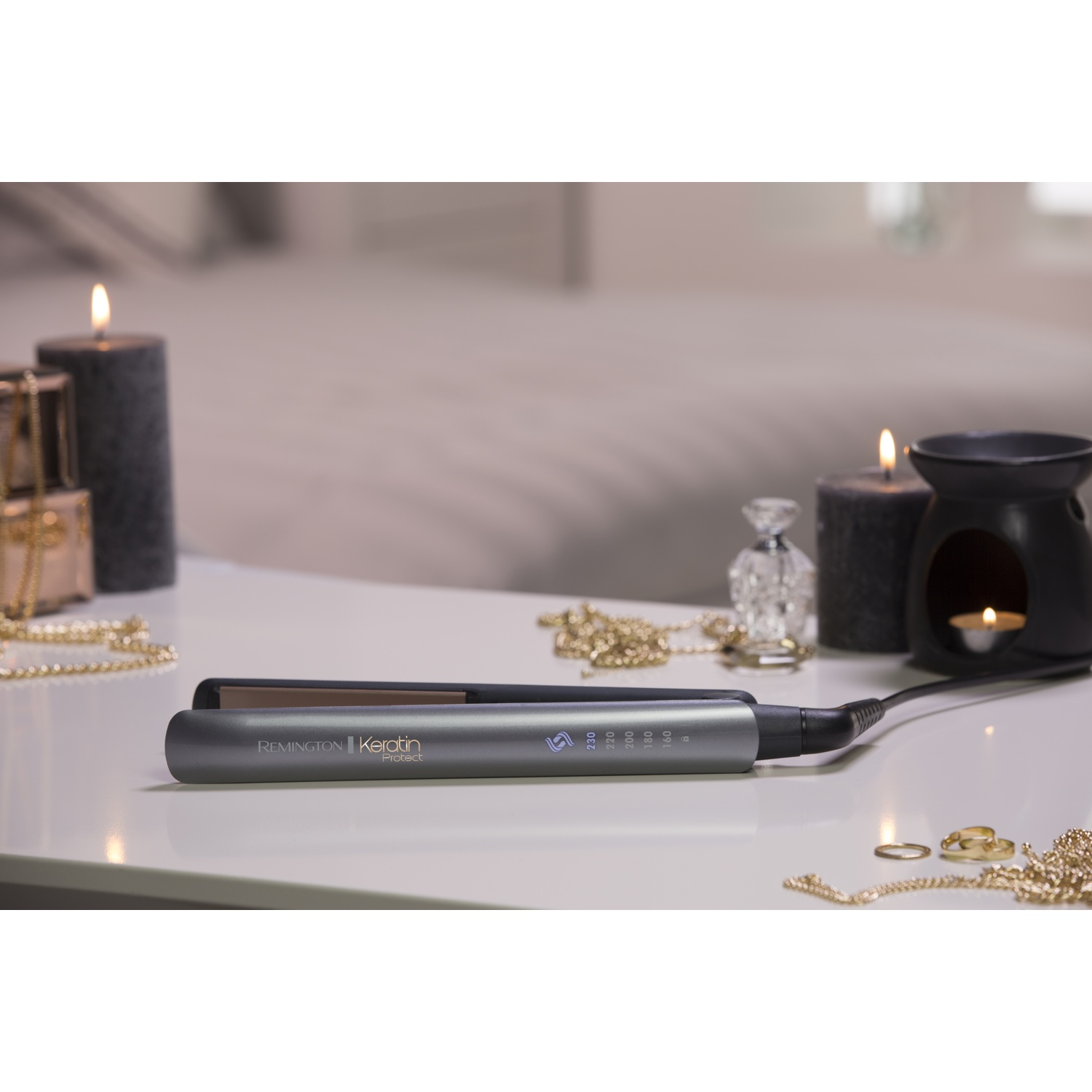 Una piastra per capelli Remington Keratin Protect grigia poggia su un tavolo bianco.