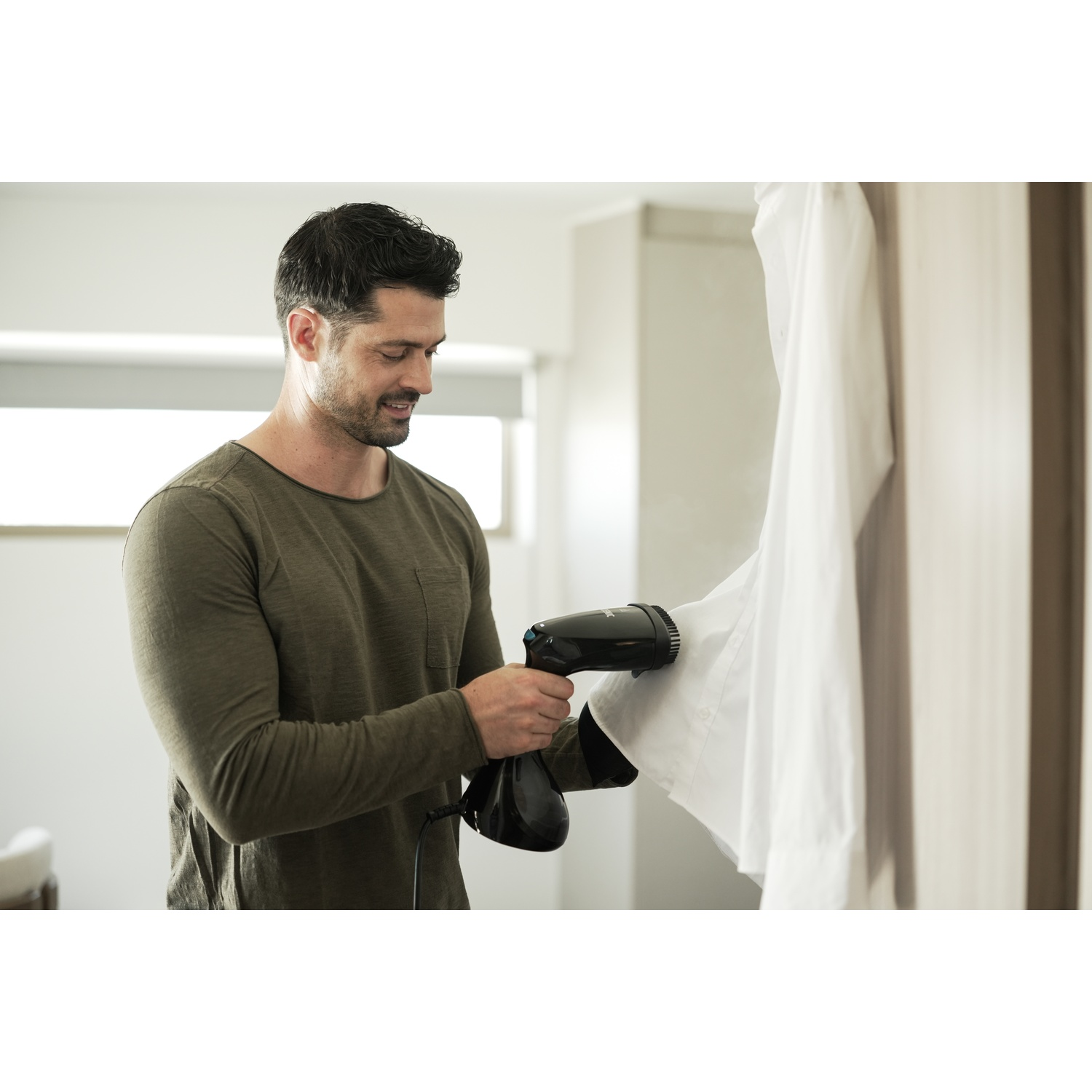 Homme défroisse chemise blanche avec défroisseur. Chemise vert foncé.