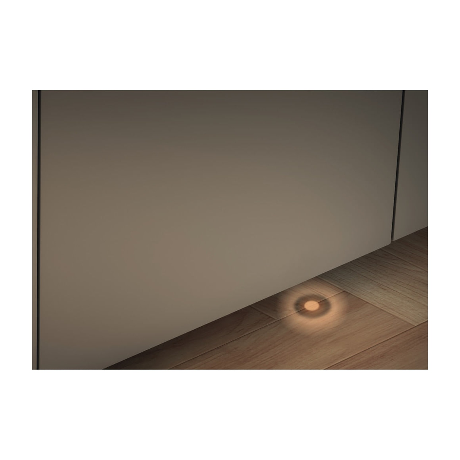 Un piccolo punto illuminato su un pavimento in legno accanto a un muro.