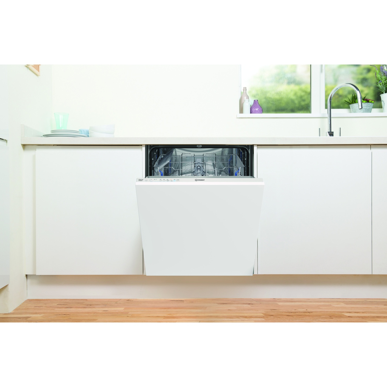 Una lavastoviglie bianca aperta in una cucina moderna con pavimento in legno.