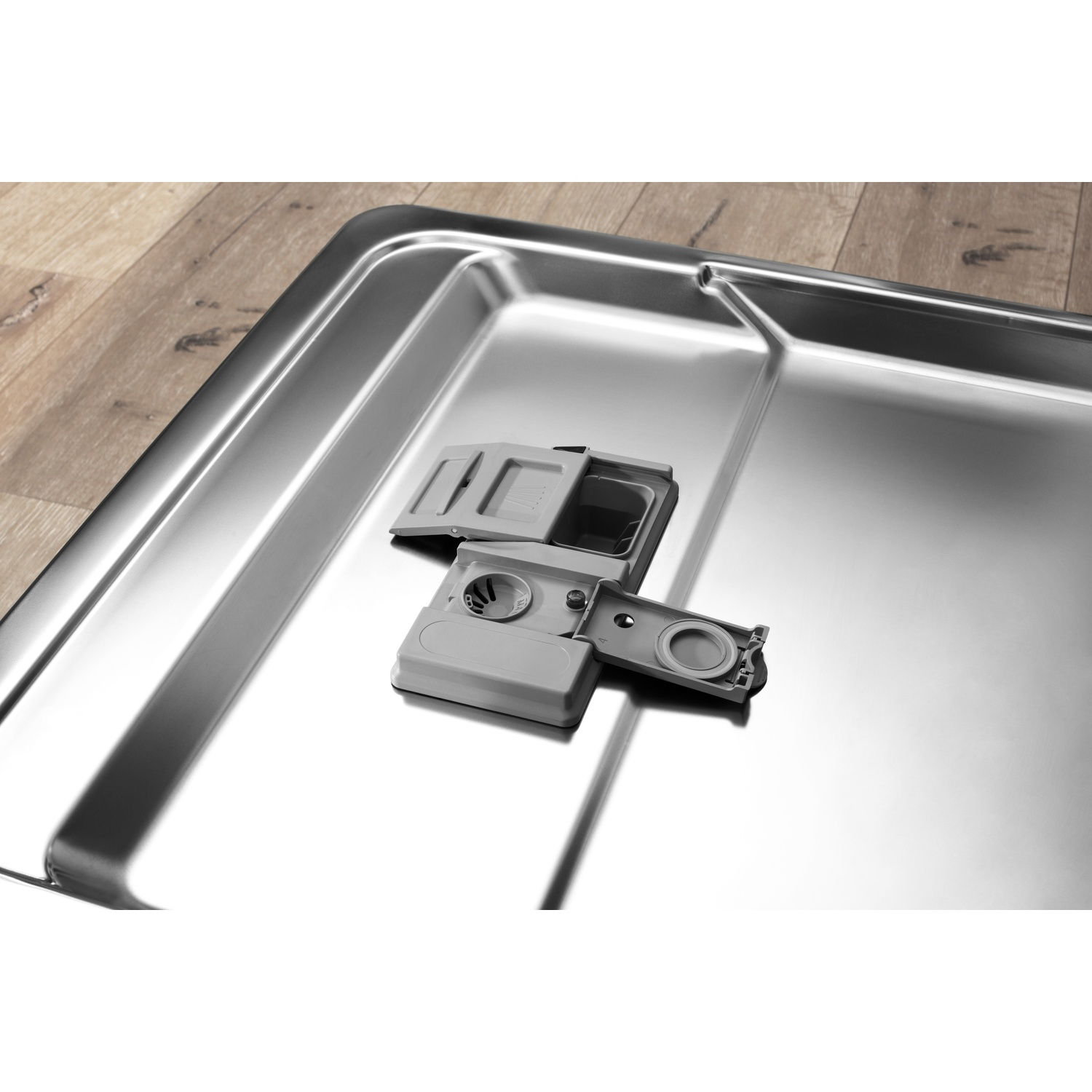 Un filtro grigio per lavastoviglie poggia su una vasca in acciaio inox.