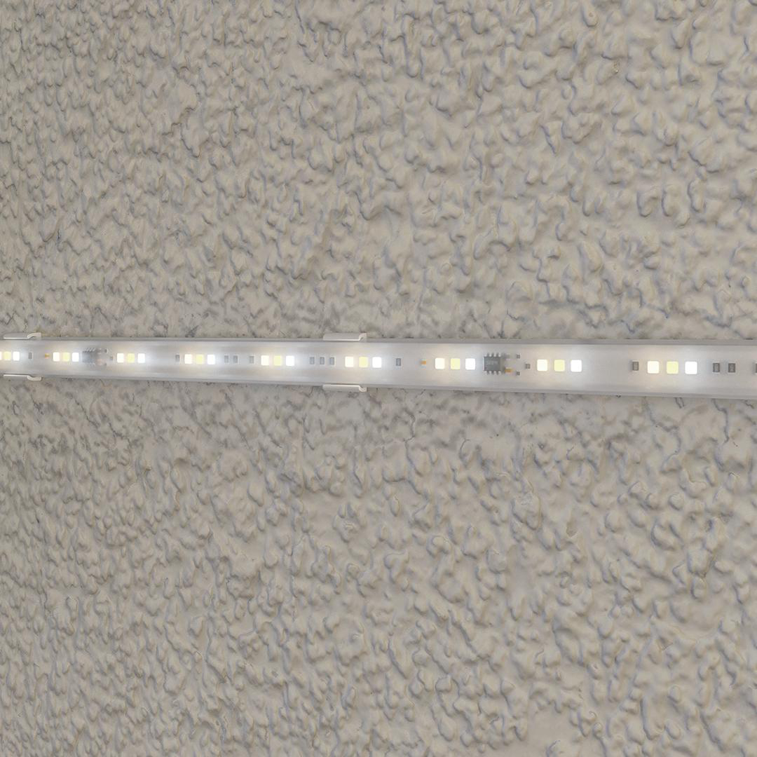 Eine LED-Lichtleiste mit weißen und warmweißen Lichtern auf einer strukturierten Wand.