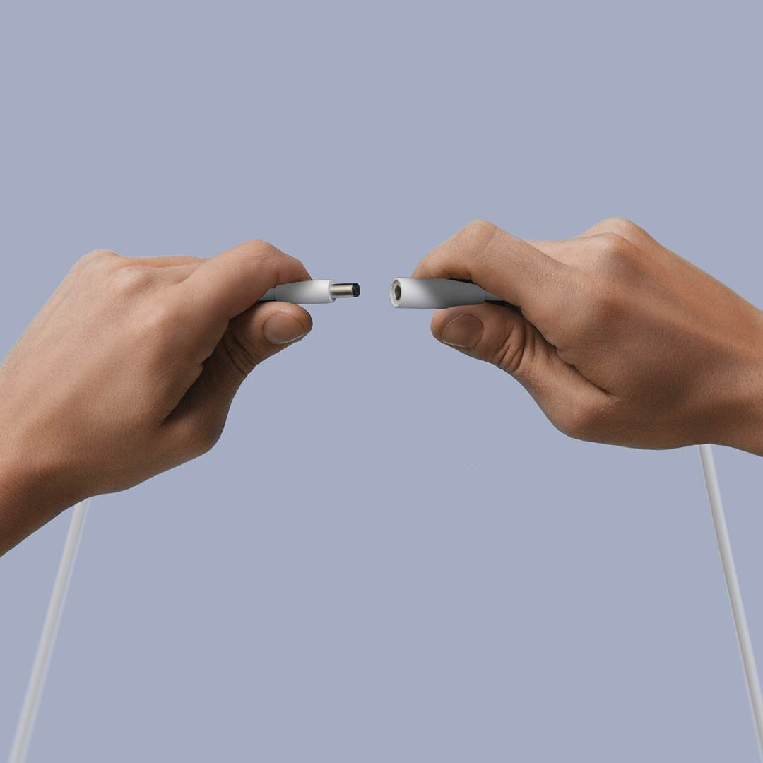 Zwei Hände verbinden ein weißes Kabel mit einem Stecker und einer Buchse.