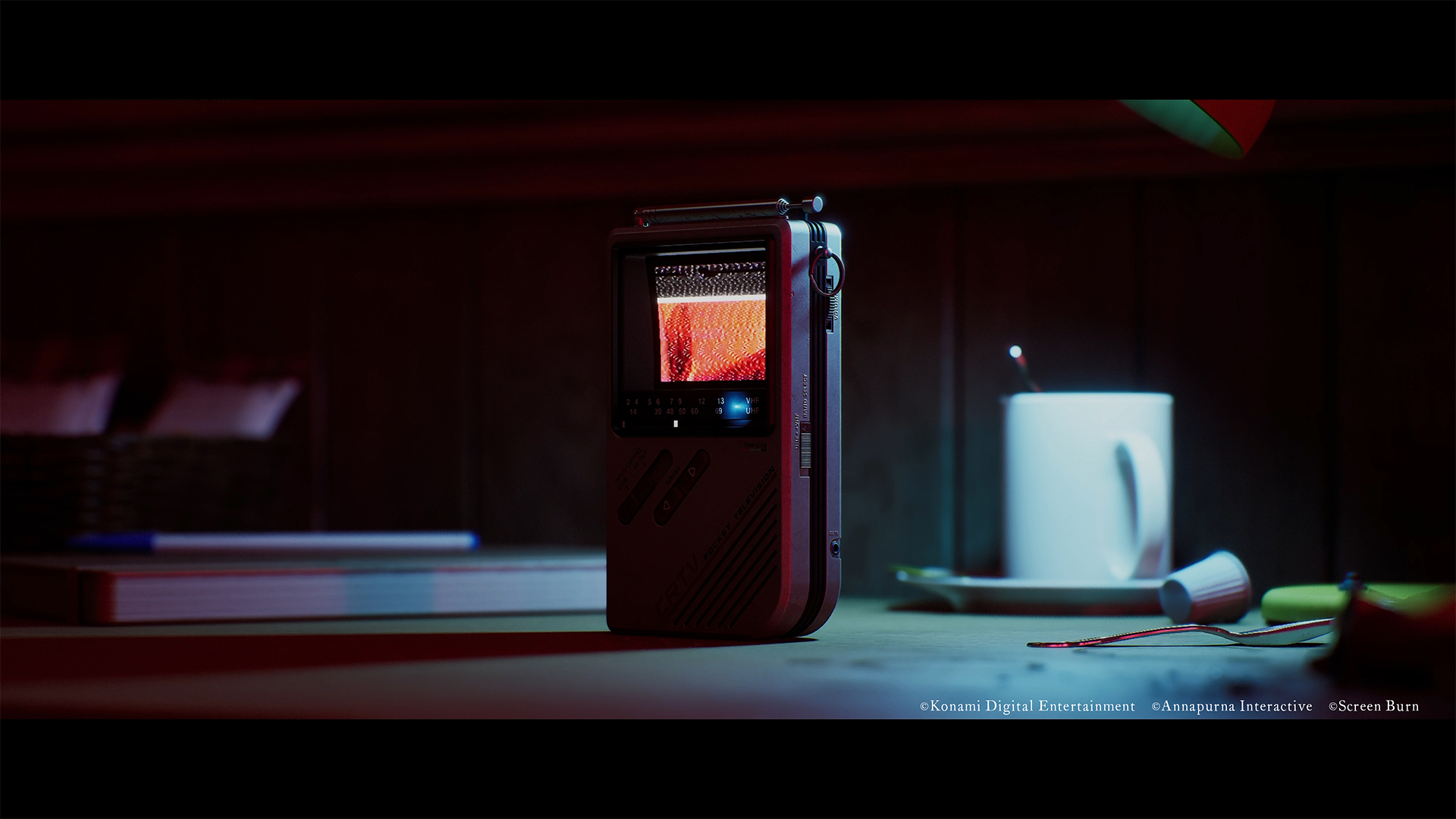 Przenośny telewizor z zakłóceniami na ekranie stoi obok kubka.