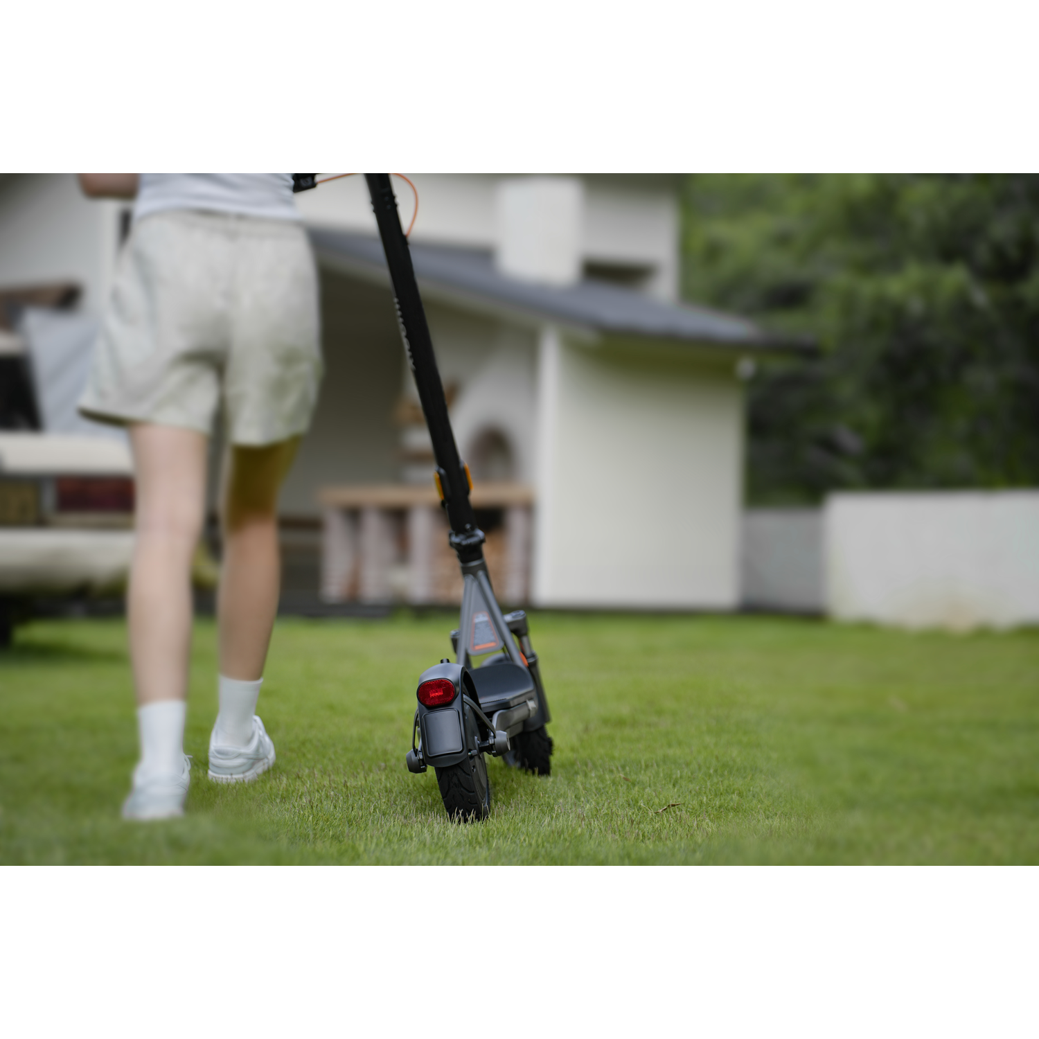 Een persoon loopt op gras naar een elektrische scooter.