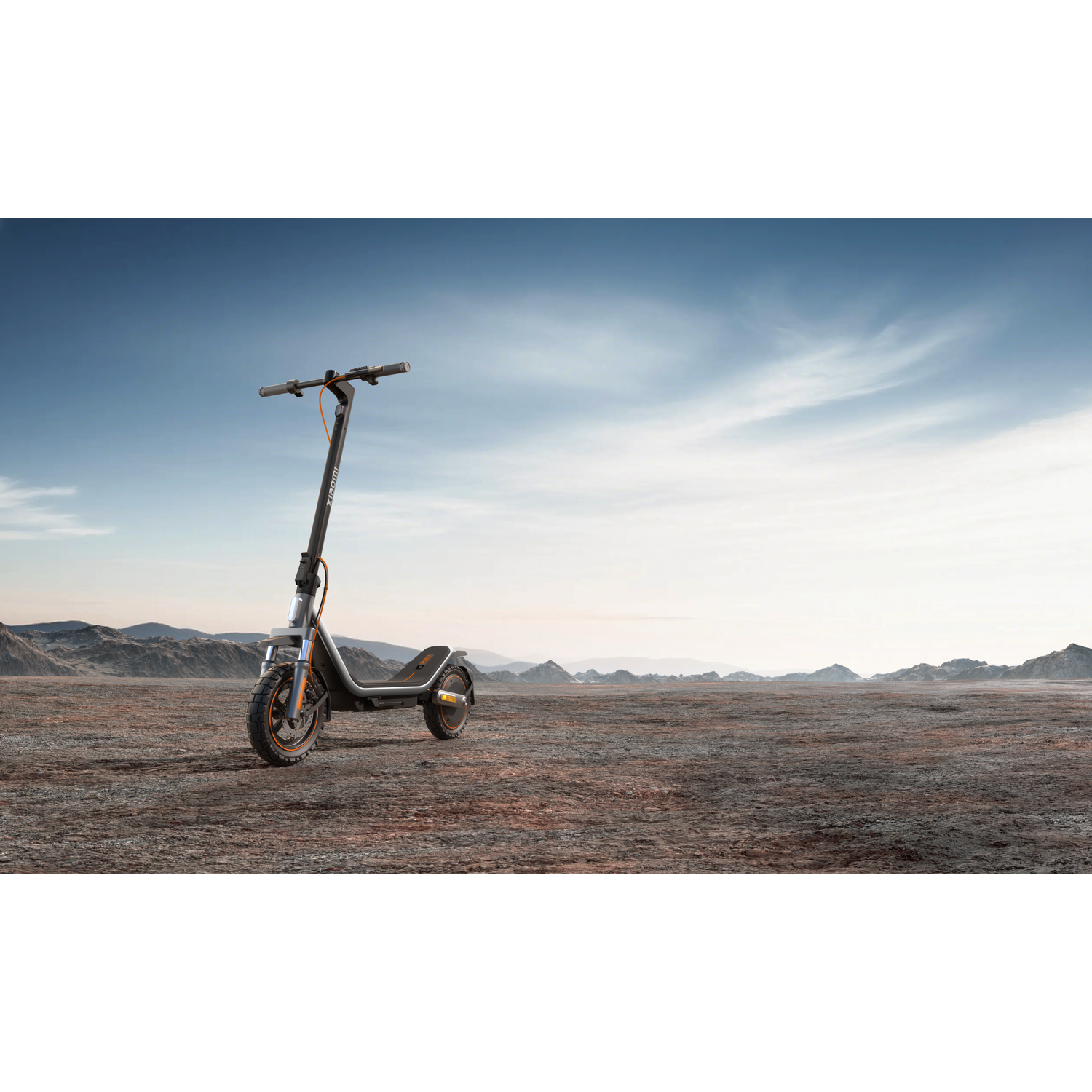 Een zwarte elektrische scooter met oranje accenten staat in een dor landschap.