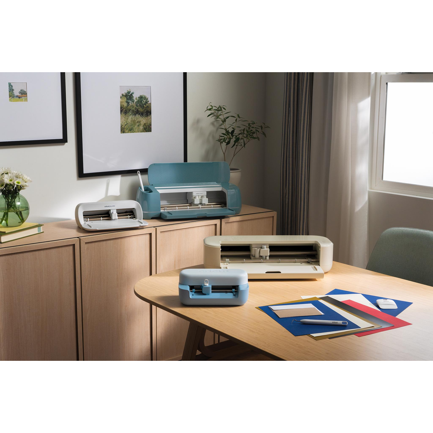 Three cutting machines and craft supplies on a wooden table.