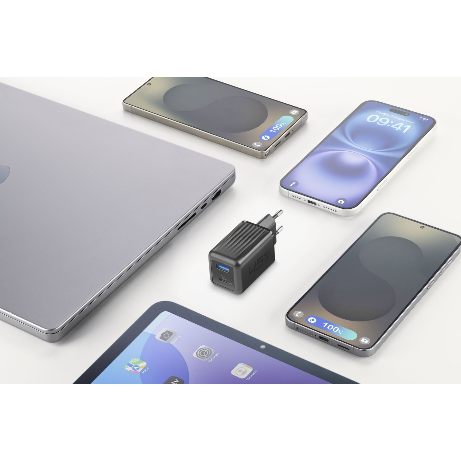 Un laptop, un caricabatterie e tre smartphone disposti su una superficie bianca.