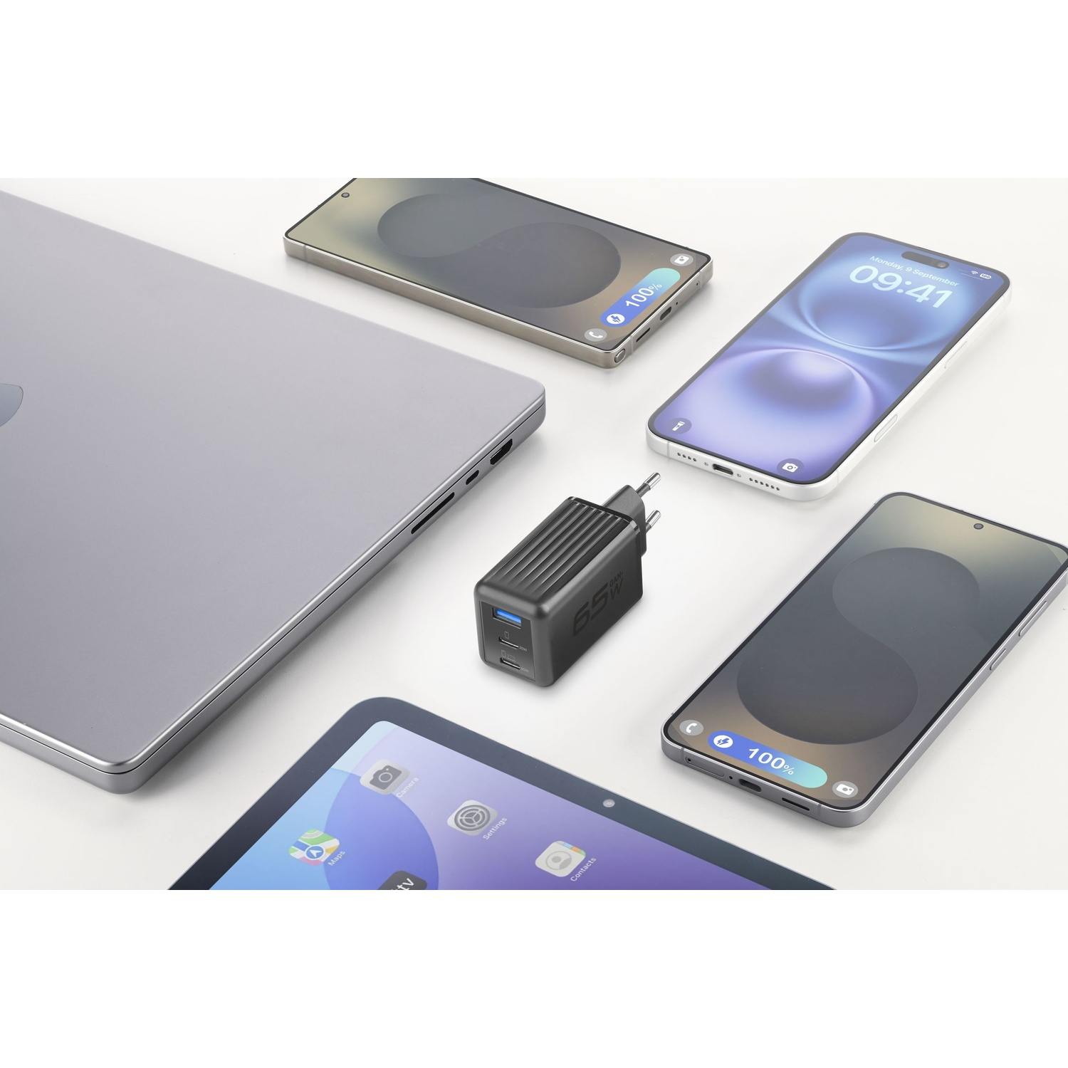 Un laptop, un caricabatterie e tre smartphone su una superficie bianca.