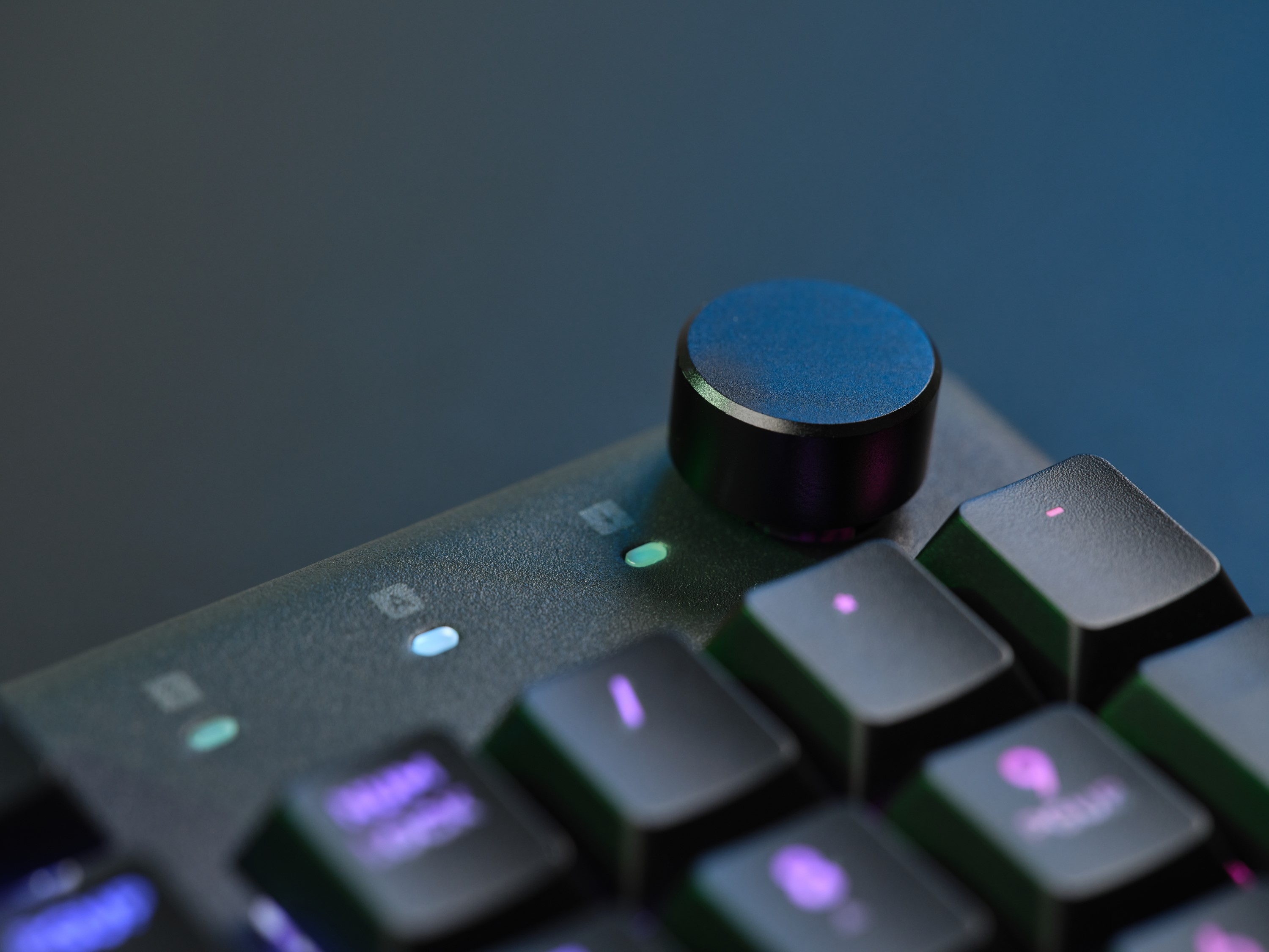 Zbliżenie czarnej klawiatury z podświetlanymi klawiszami i pokrętłem.