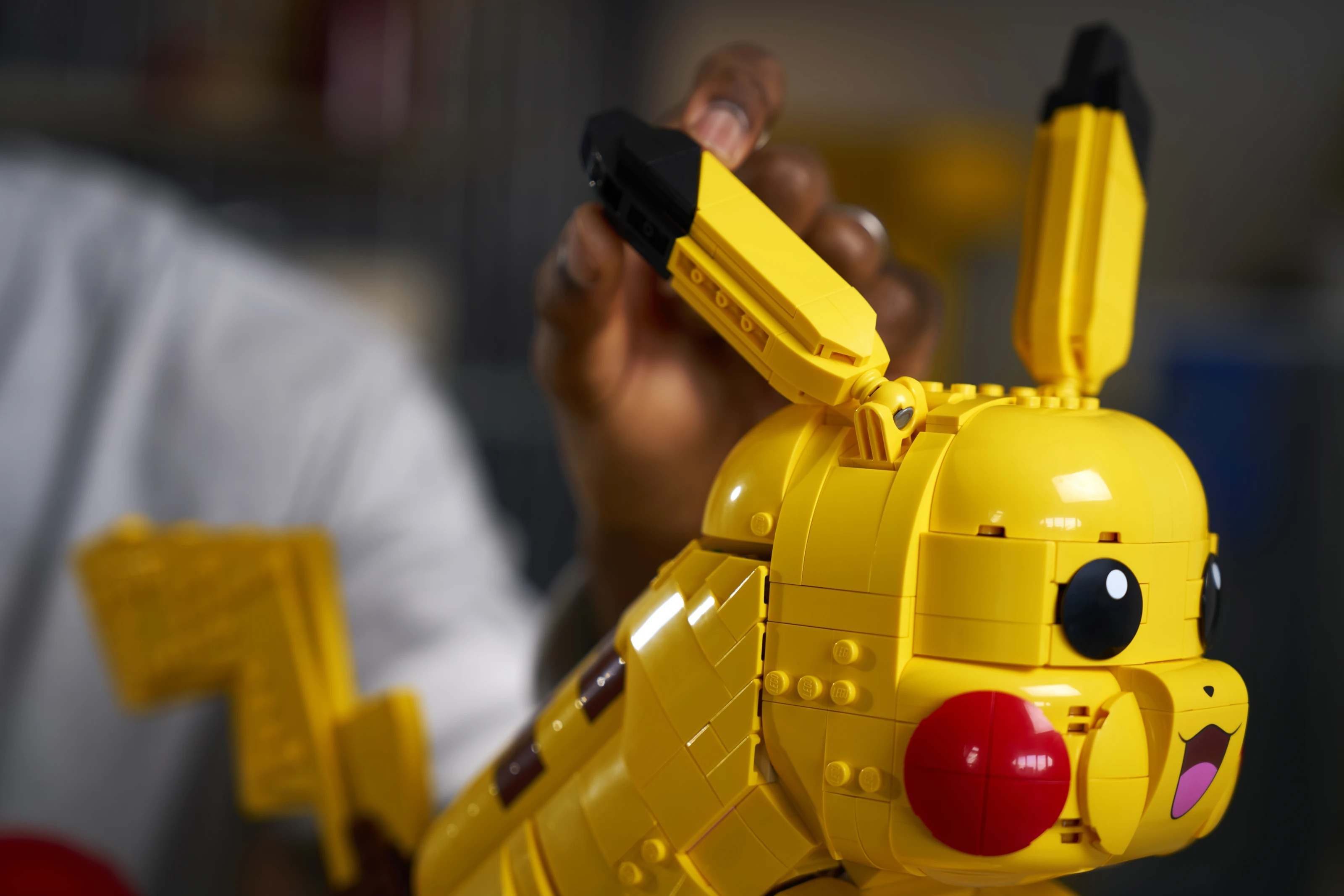 Osoba składa żółtego Pikachu z klocków Lego.