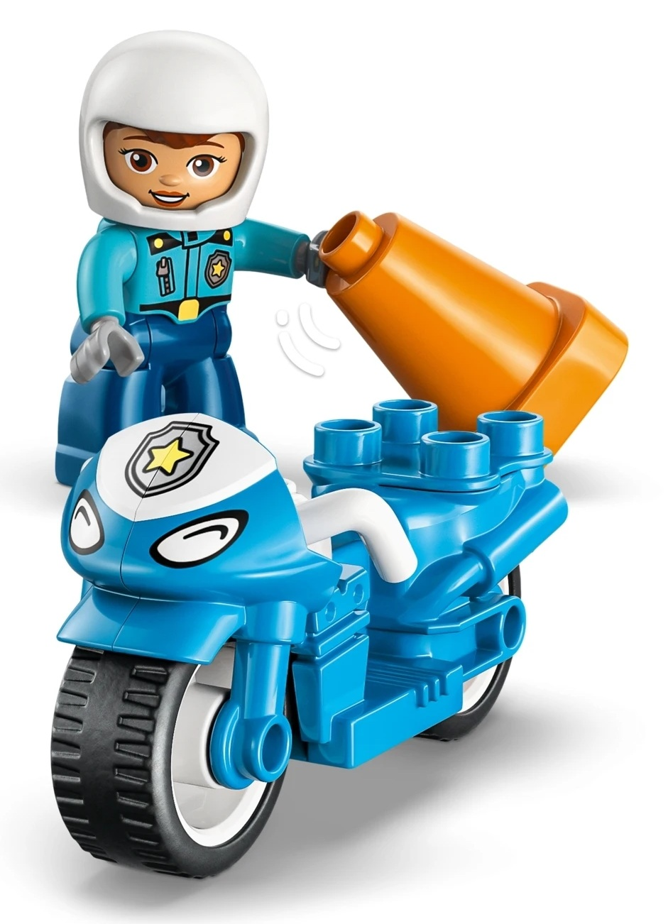 Policjant w kolorze niebieskim z kaskiem trzyma pomarańczowy pachołek obok niebieskiego motocykla.