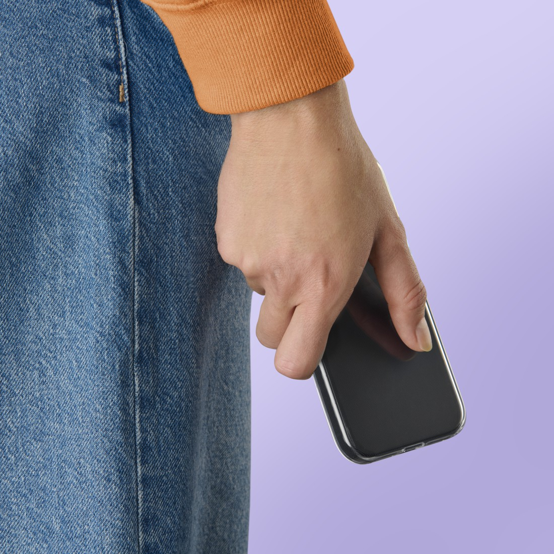 Eine Hand hält ein schwarzes Smartphone vor einer Jeans und einem lila Hintergrund.