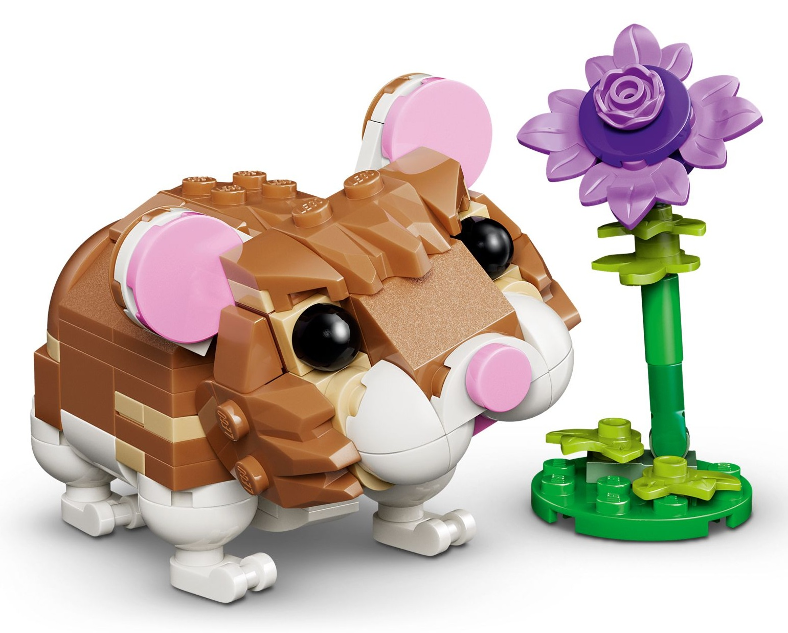 Brązowy chomik LEGO z różowymi uszami stoi obok fioletowego kwiatka LEGO.