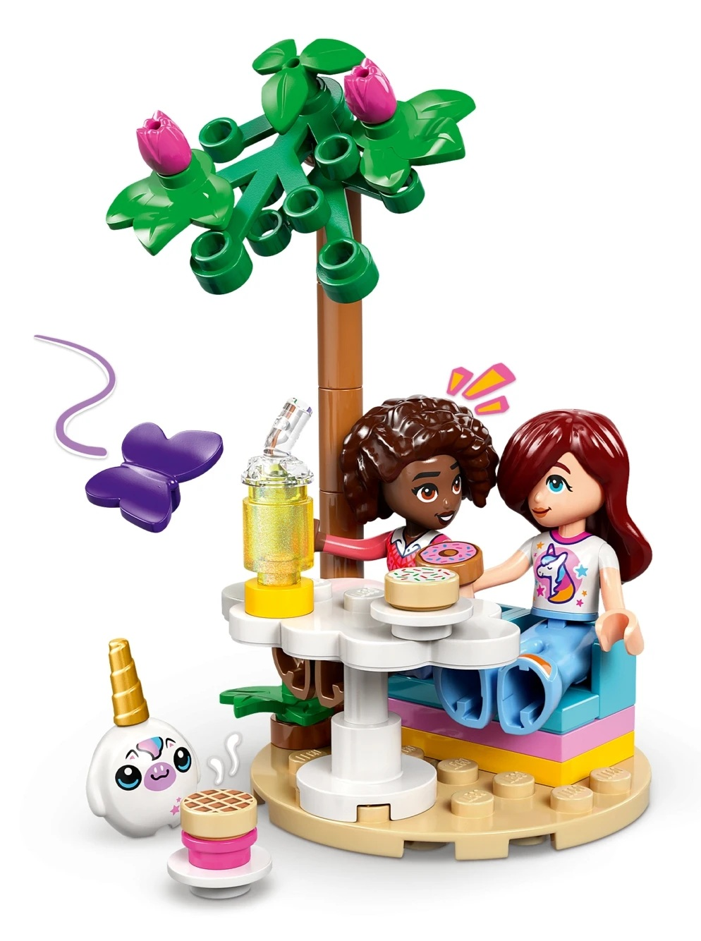 Dwie przyjaciółki Lego siedzą przy stole pod drzewem, dzieląc się pączkami. W pobliżu stworzenie jednorożca.