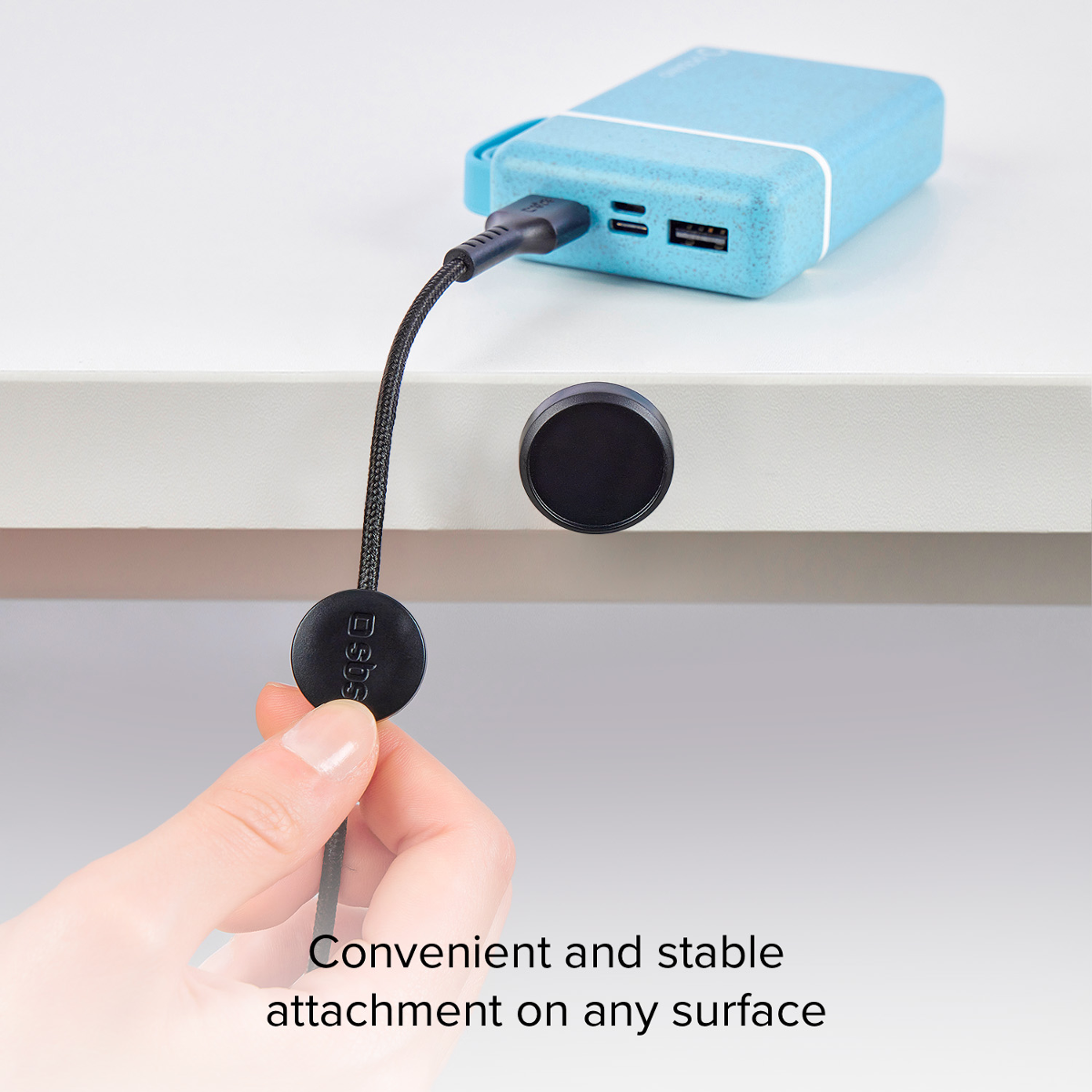 Ein blauer Akku ist mit einem Kabel verbunden, das an einem Tisch befestigt ist.