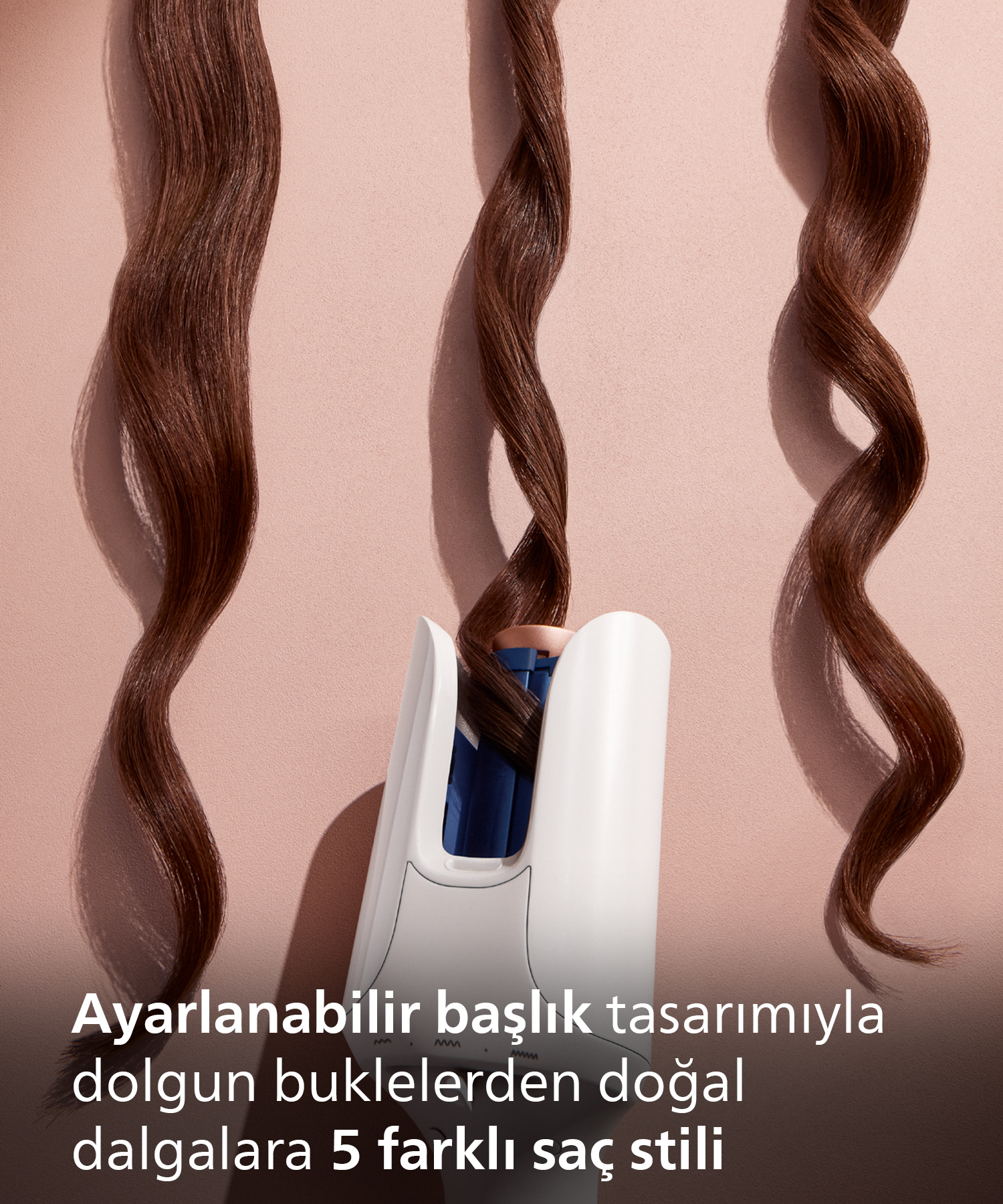Beyaz saç şekillendirme cihazı, bej zeminde kahverengi saçları kıvırıyor.