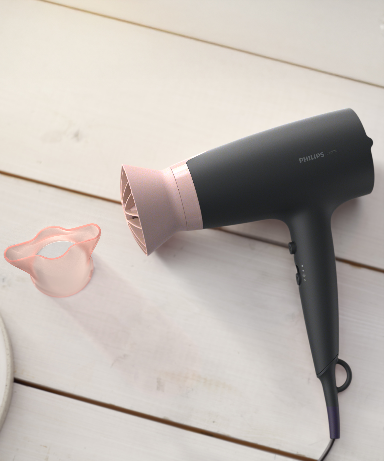 Ahşap masa üzerinde gül altın rengi vurgulu siyah Philips saç kurutma makinesi.