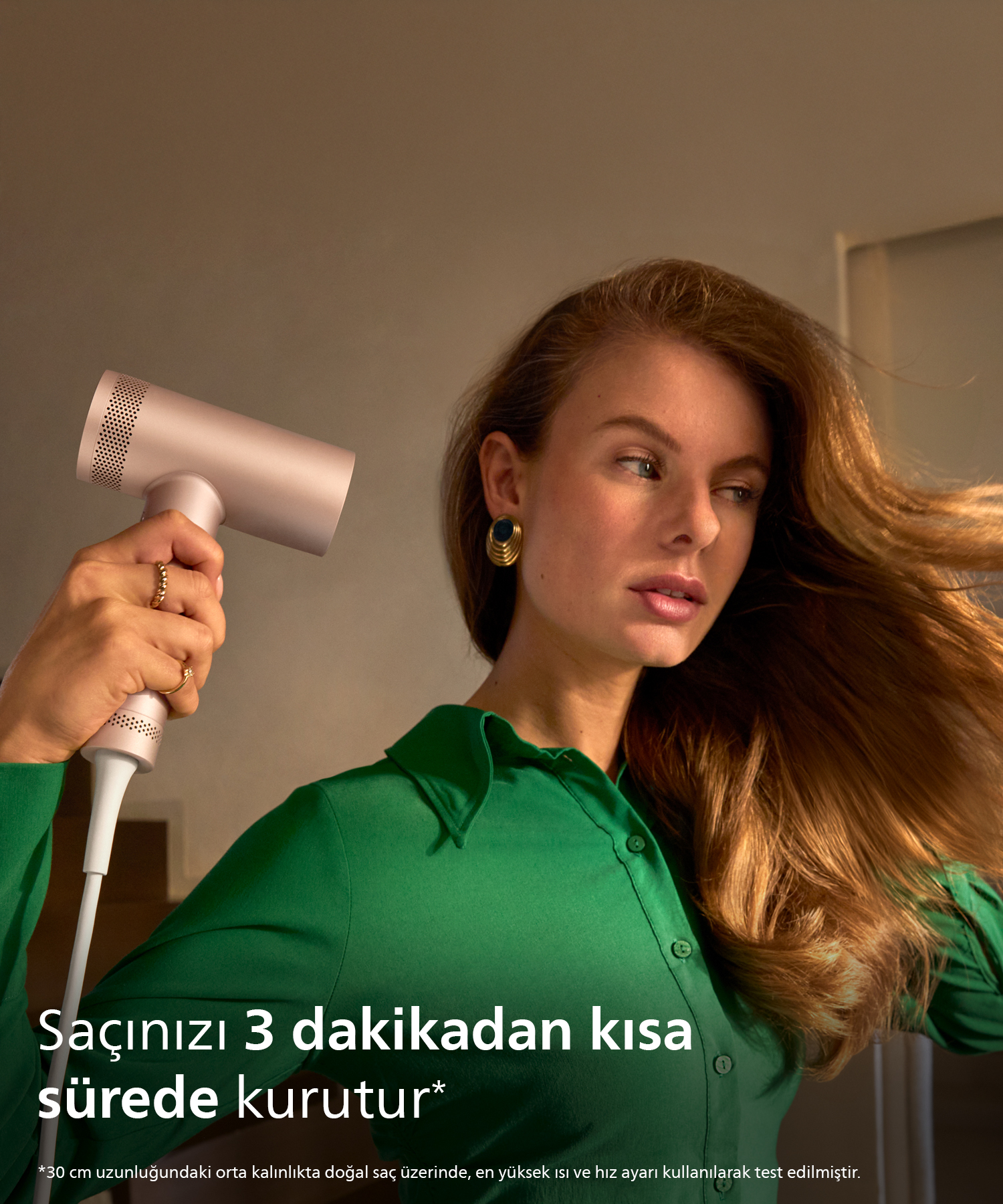Uzun saçlı bir kadın, saçını kurutmak için pembe bir saç kurutma makinesi kullanıyor.