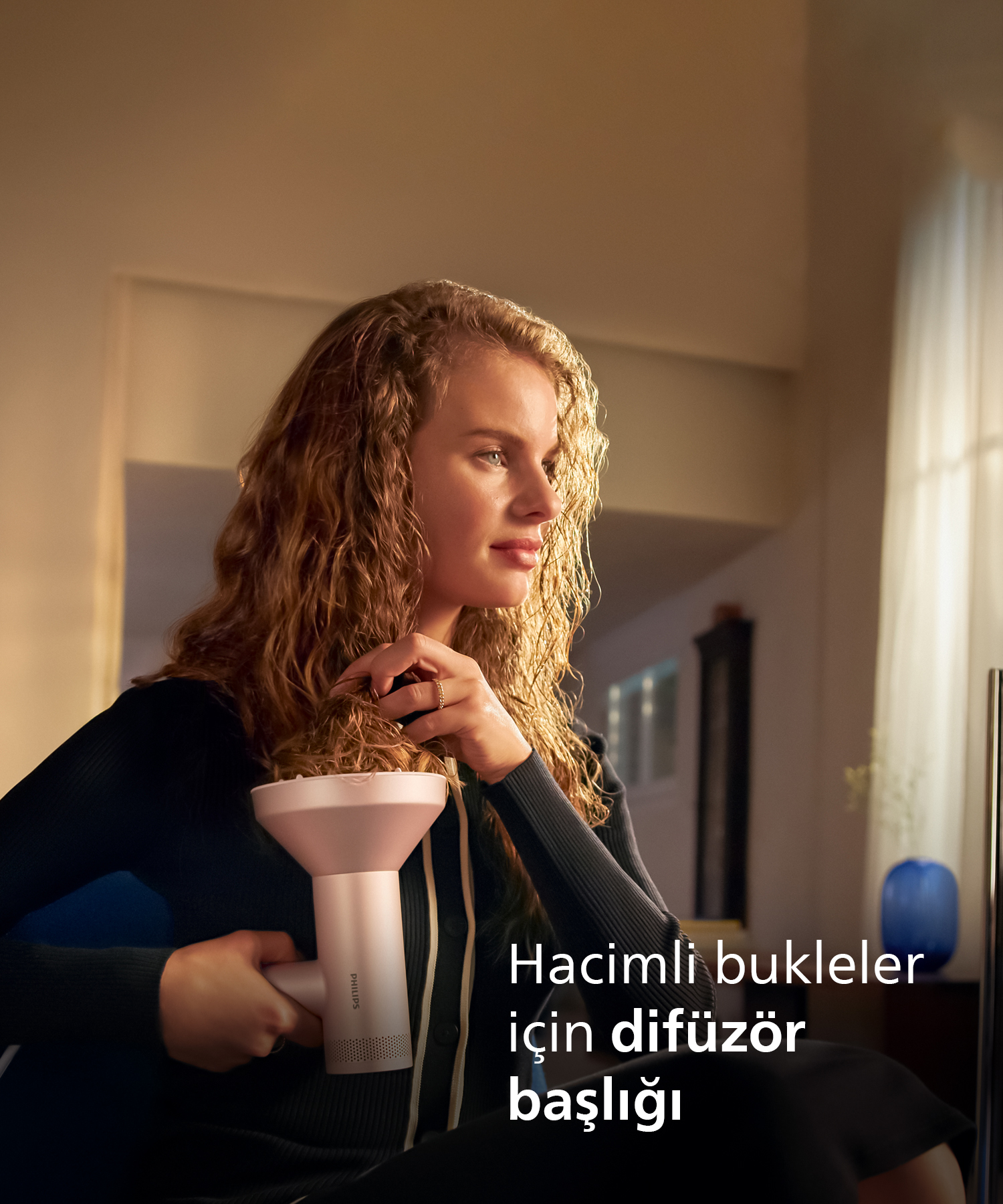 Kıvırcık saçlı kadın saç kurutma makinesi için difüzör başlığı tutuyor.