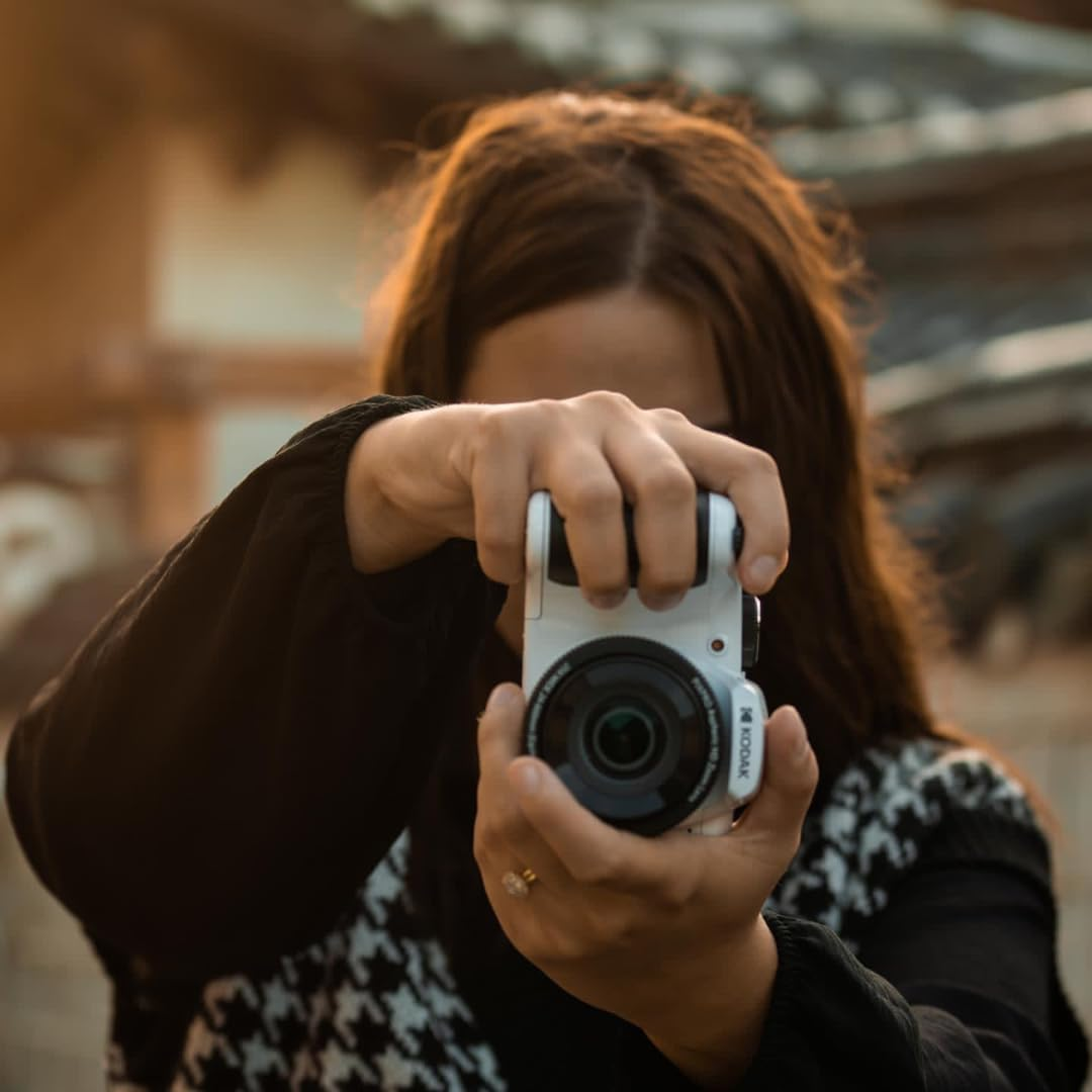 Bir kadın beyaz bir kamera tutuyor, fotoğraf çekiyor.