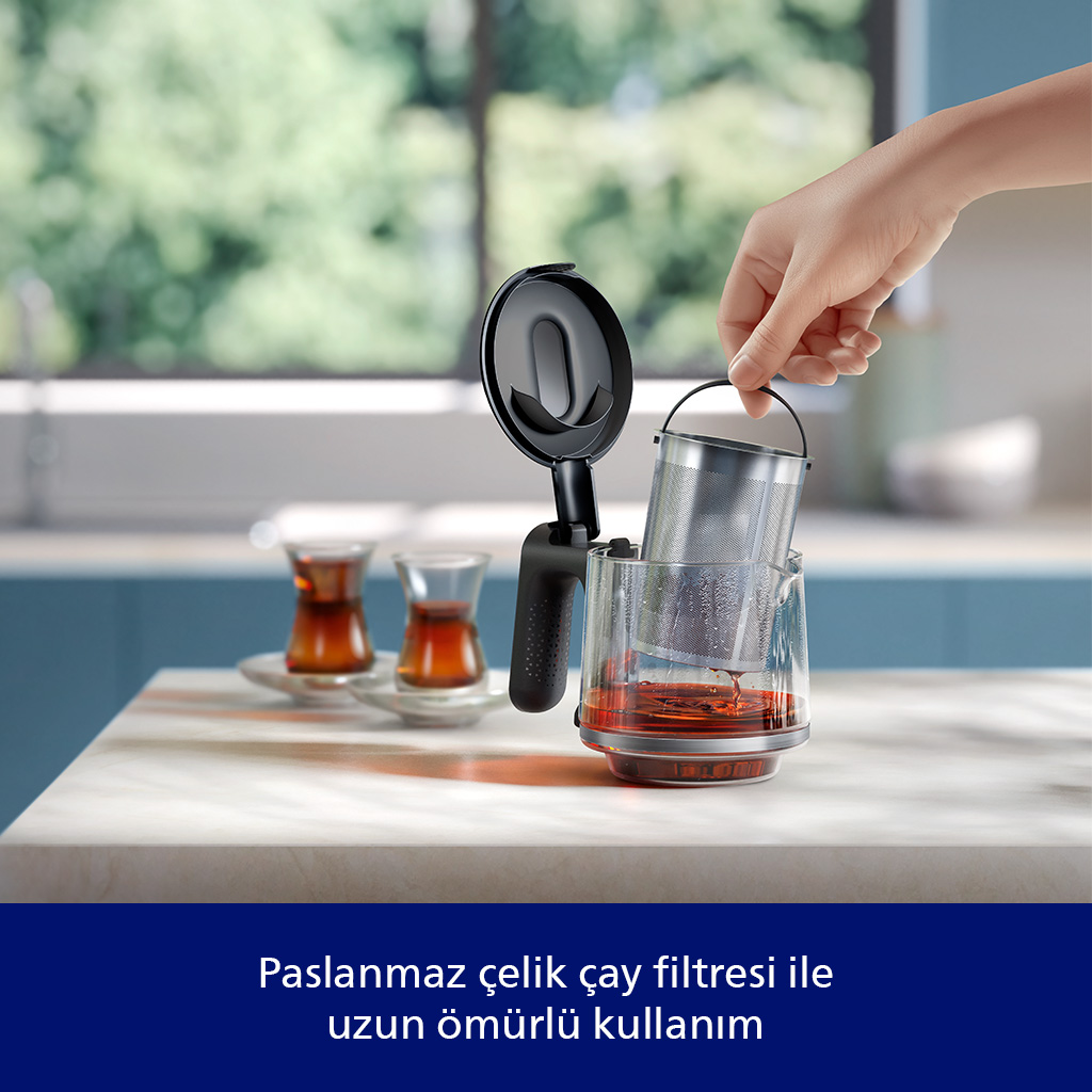 Bir el, çaylı cam demliğe metal çay filtresi yerleştiriyor.