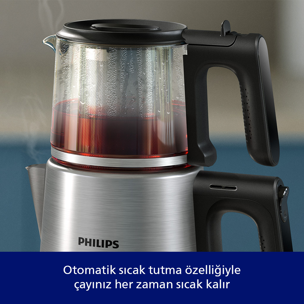 Cam demliği ve siyah saplı gümüş çay makinesi. Buhar yükseliyor.