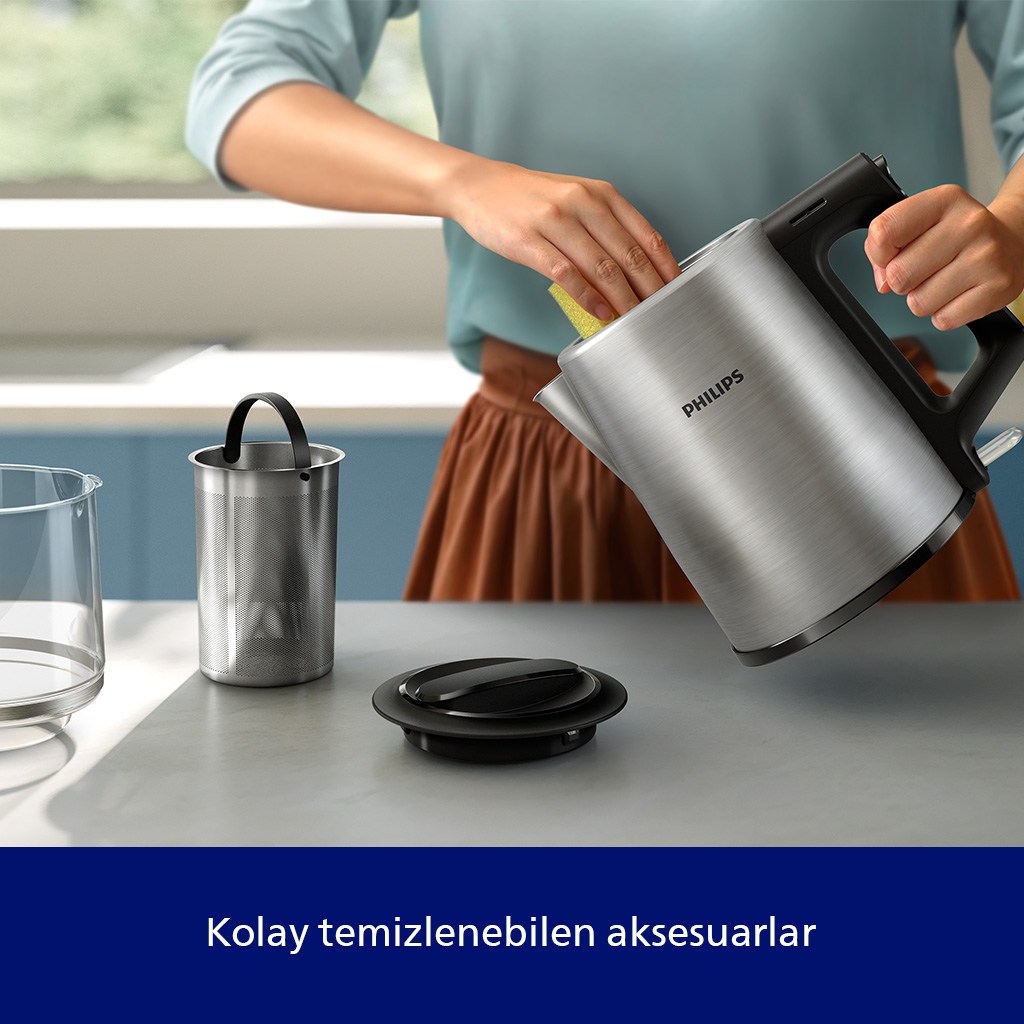 Bir kişi sarı süngerle gümüş rengi su ısıtıcısını temizliyor.