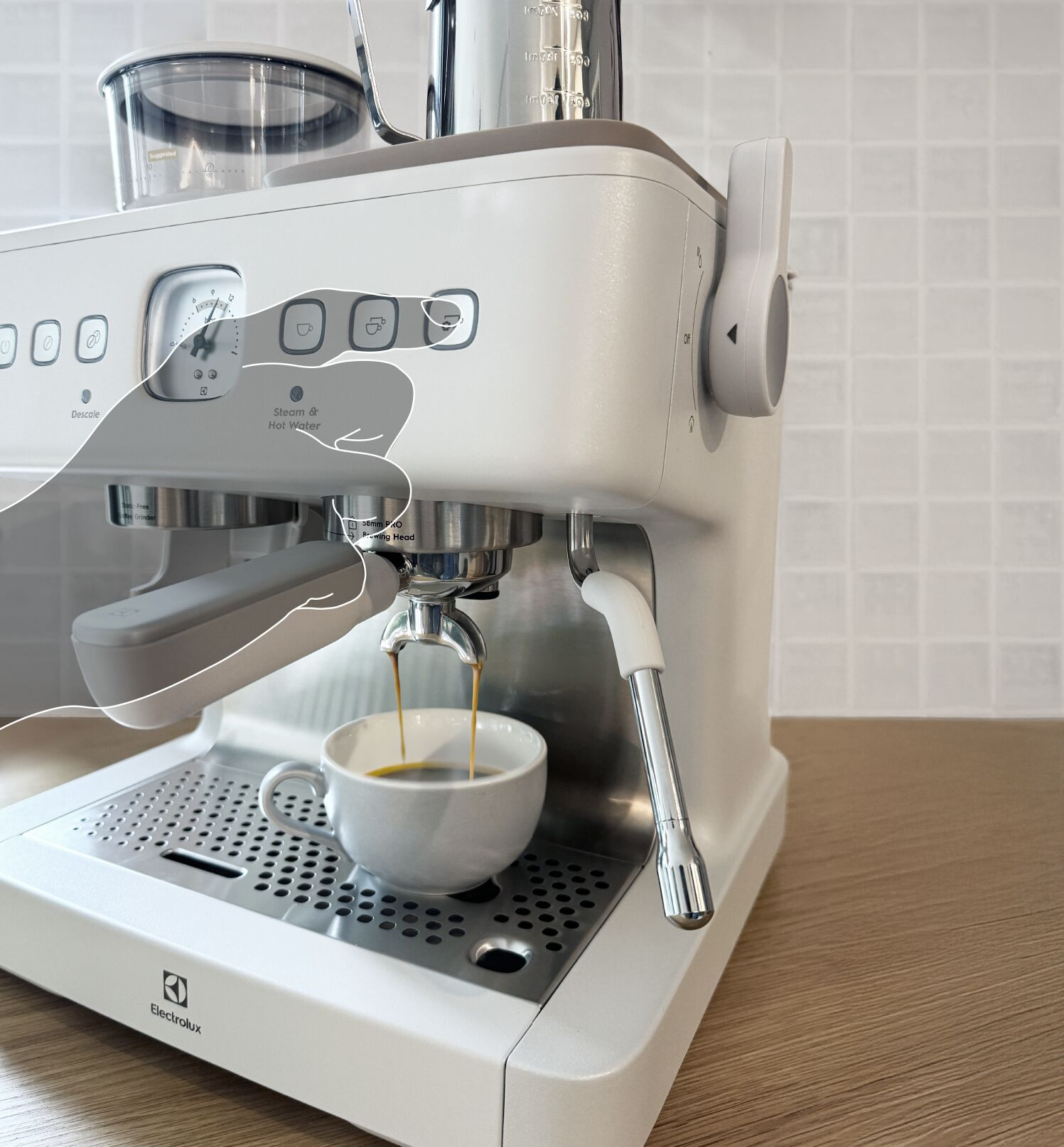 Bir el, fincana kahve demleyen beyaz bir espresso makinesini çalıştırıyor.